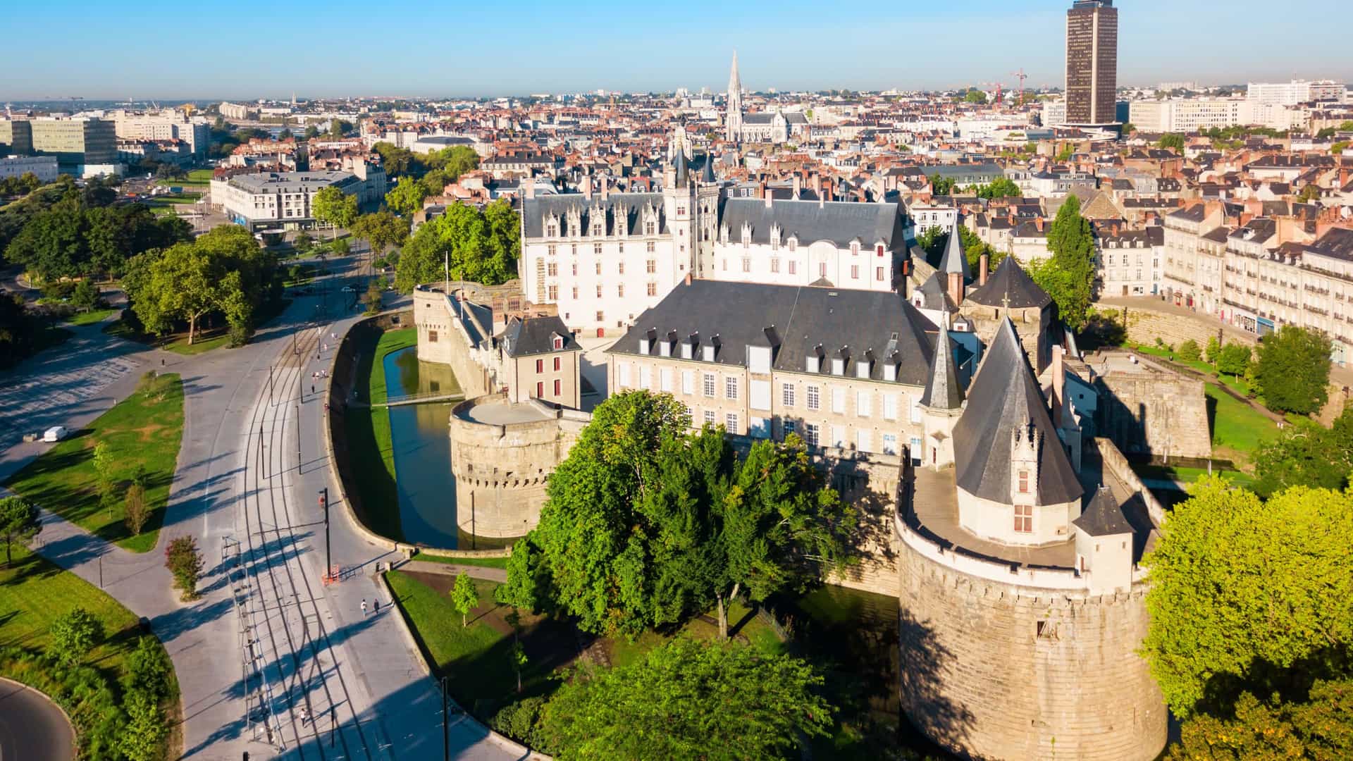 "An aerial view of the historic city of Nantes, France, with the medieval Château des Ducs de Bretagne (Castle of the Dukes of Brittany) in the foreground and the city skyline in the background. "
