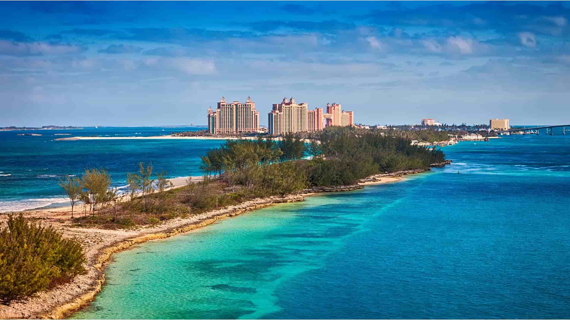A stunning aerial view of the turquoise waters and white-sand beaches around Paradise Island in Nassau, Bahamas, with the Atlantis resort visible in the distance.