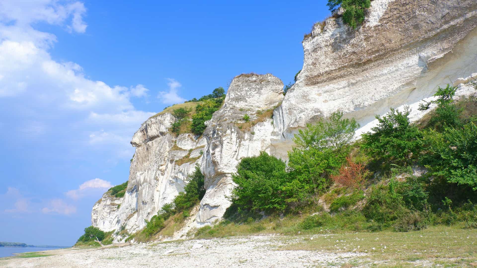 Sheer white cliffs covered with trees and bushes overlook the Danube River, a natural landmark near Nikopol, Bulgaria, on a beautiful sunny day.