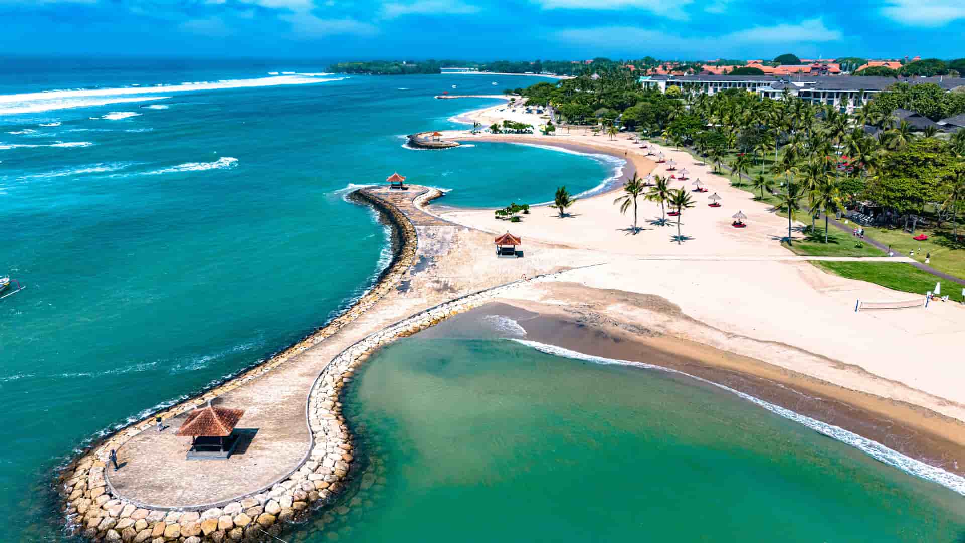 "An aerial view of the scenic coastline of Nusa Dua, Bali, Indonesia, with a serene lagoon and white sandy beach, a perfect tourist destination. "