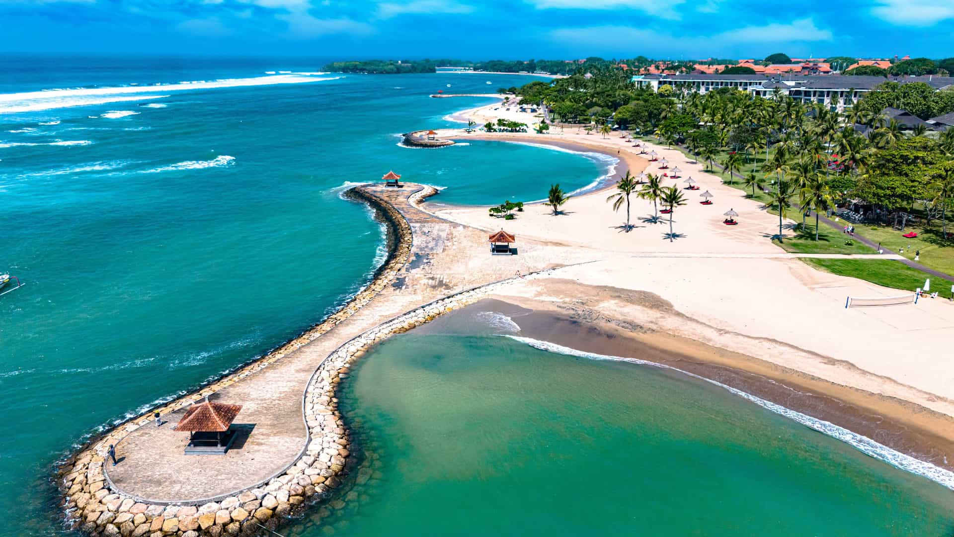 "An aerial view of the scenic coastline of Nusa Dua, Bali, Indonesia, with a serene lagoon and white sandy beach, a perfect tourist destination. "