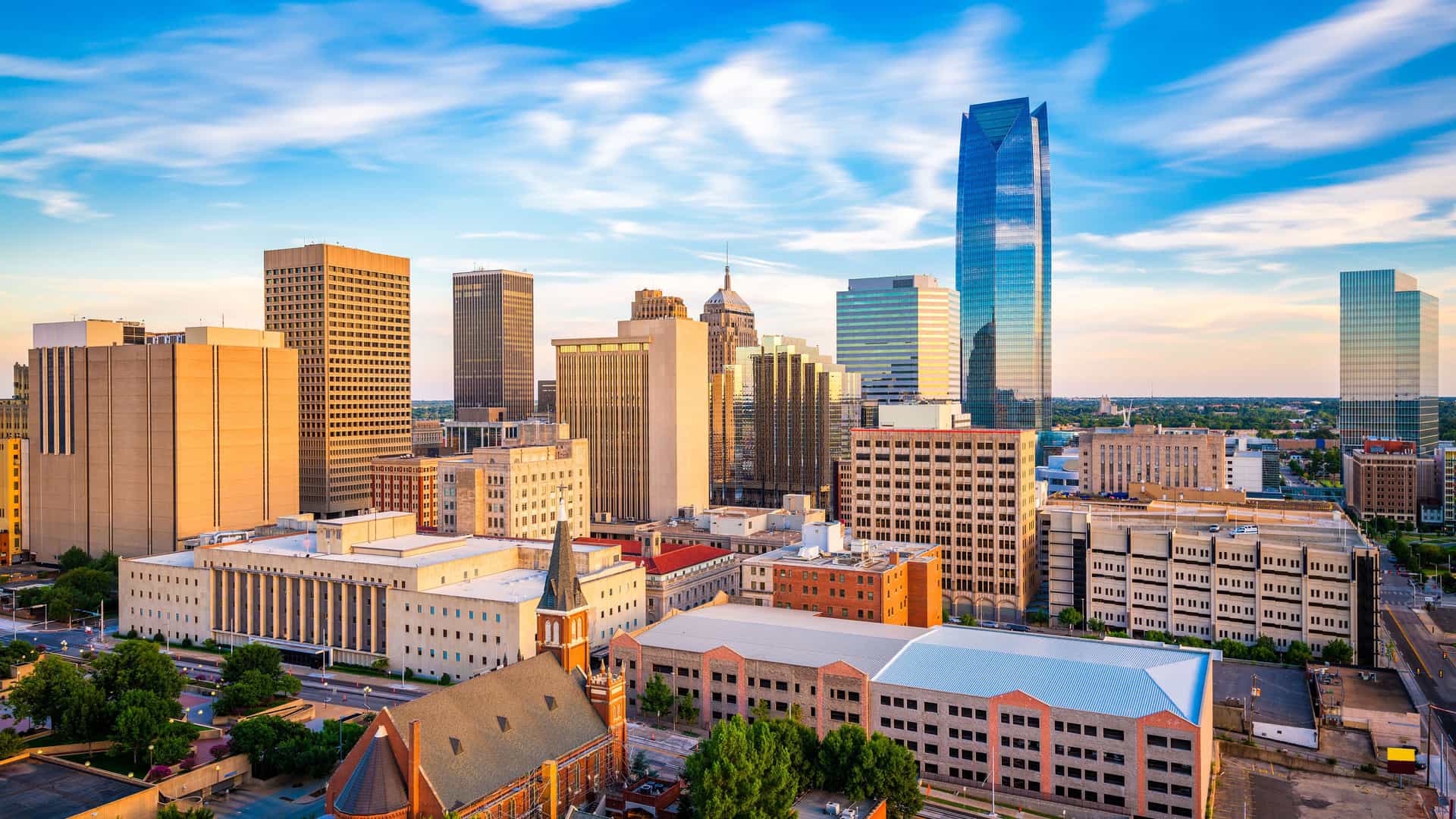 "A vibrant panoramic view of the Oklahoma City skyline with the Devon Energy Tower and other skyscrapers at sunset on a beautiful sunny day. "