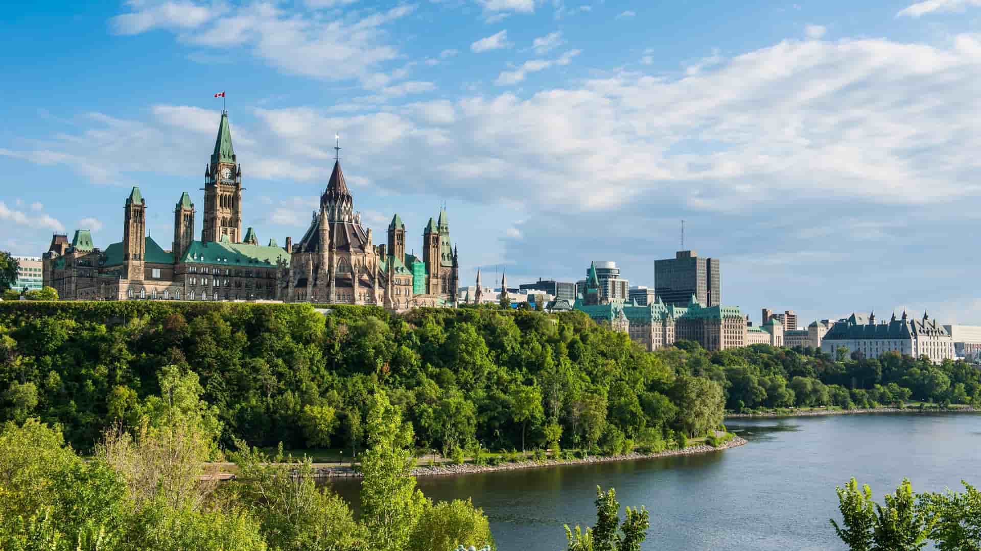 A beautiful panoramic shot of the Ottawa skyline and the Parliament Hill buildings, seen from across the Ottawa River, a landmark tourist destination.