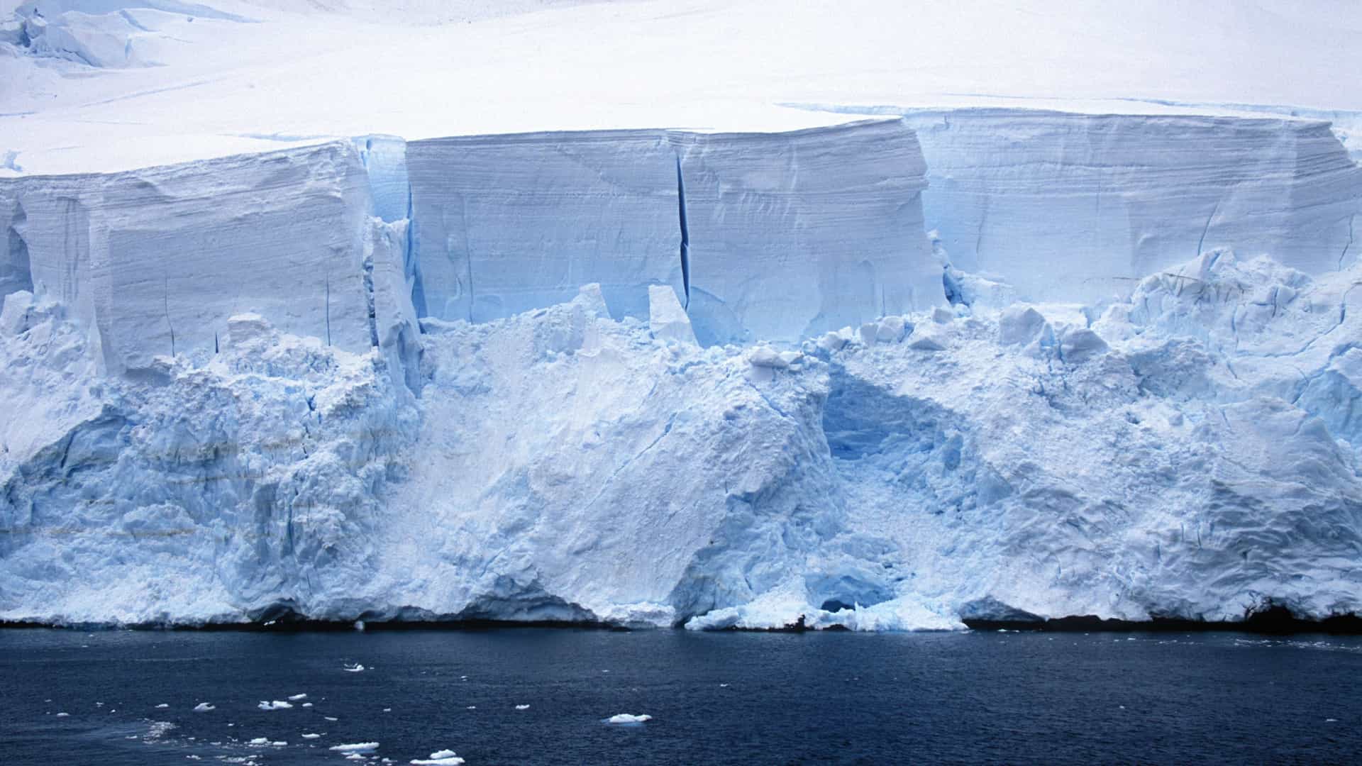 A huge glacier wall with jagged edges and deep cracks, a beautiful landmark in the waters of Paradise Bay, Antarctica.