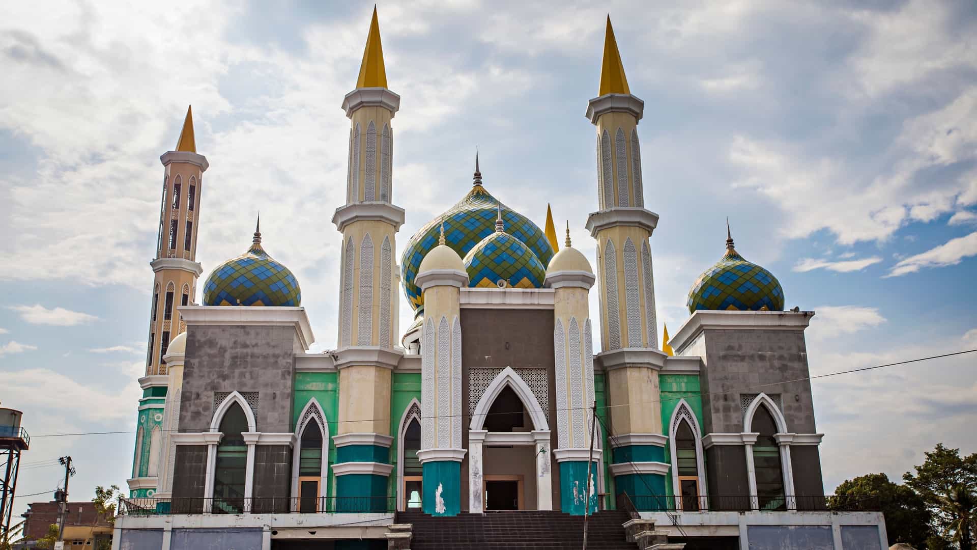 The brightly colored Islamic Center of Pare-Pare, Indonesia, with multiple yellow-tipped minarets and blue patterned domes.