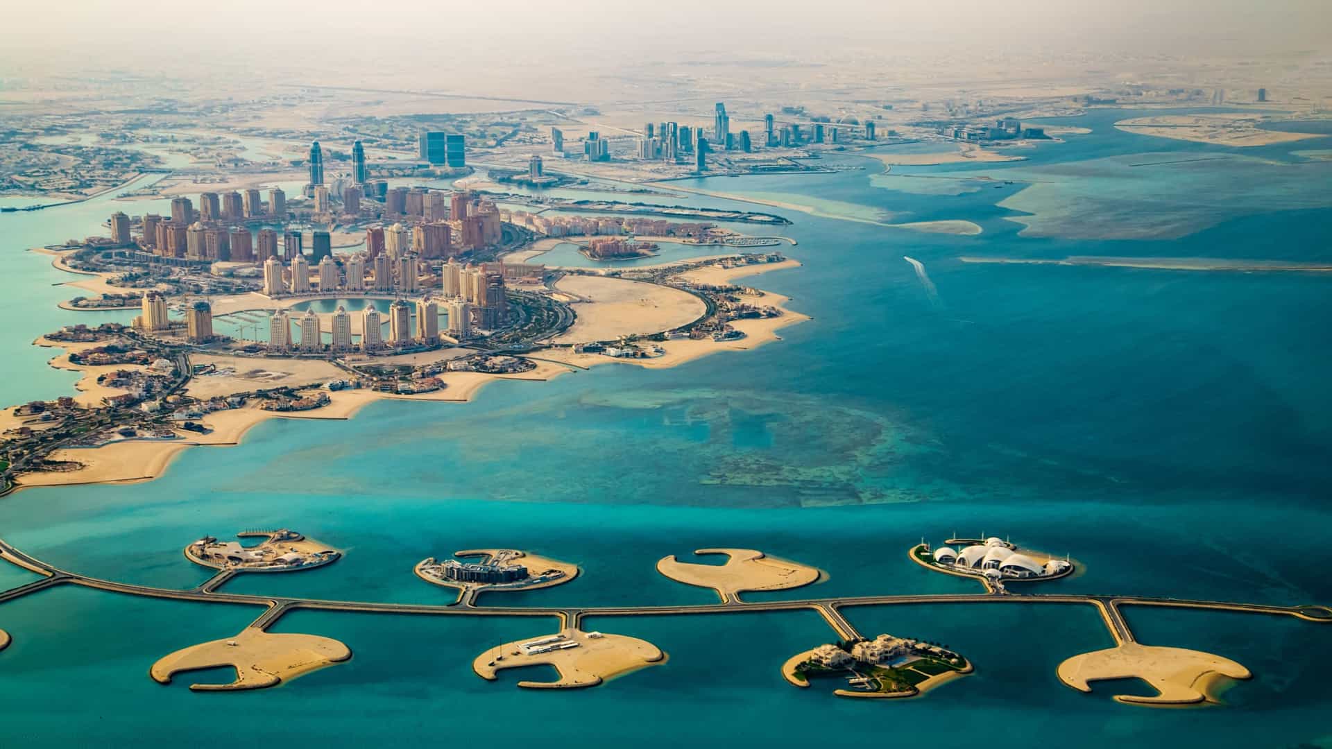 An aerial shot of "The Pearl" in Doha, Qatar, a man-made island with modern buildings in the shape of a string of pearls in the Persian Gulf.