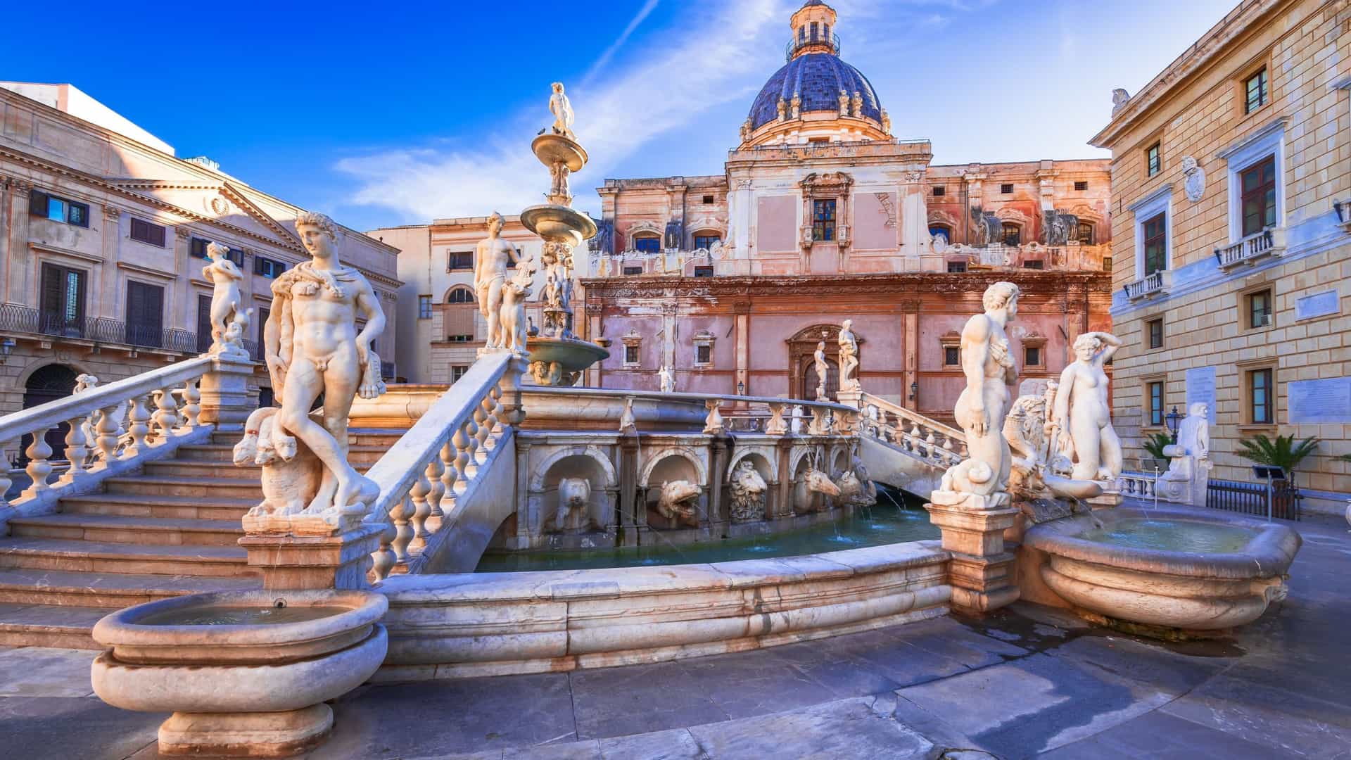 A close-up view of the Pretoria fountain in South Africa, a beautiful historic landmark with multiple levels and classical marble statues in front of an ornate building.