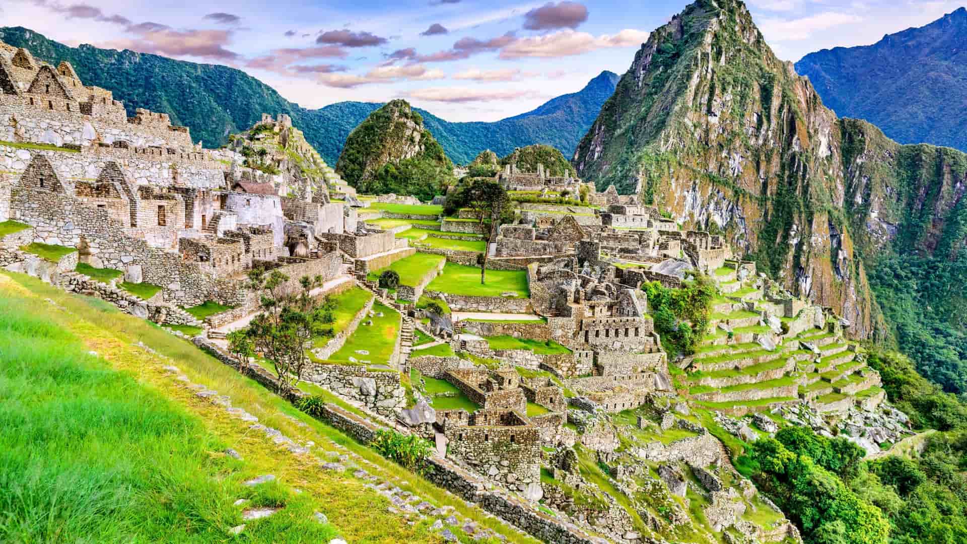 A breathtaking panoramic view of the ancient Inca citadel of Machu Picchu, a UNESCO World Heritage site, showcasing its stone structures and terraced fields amid the Andes Mountains in Peru.