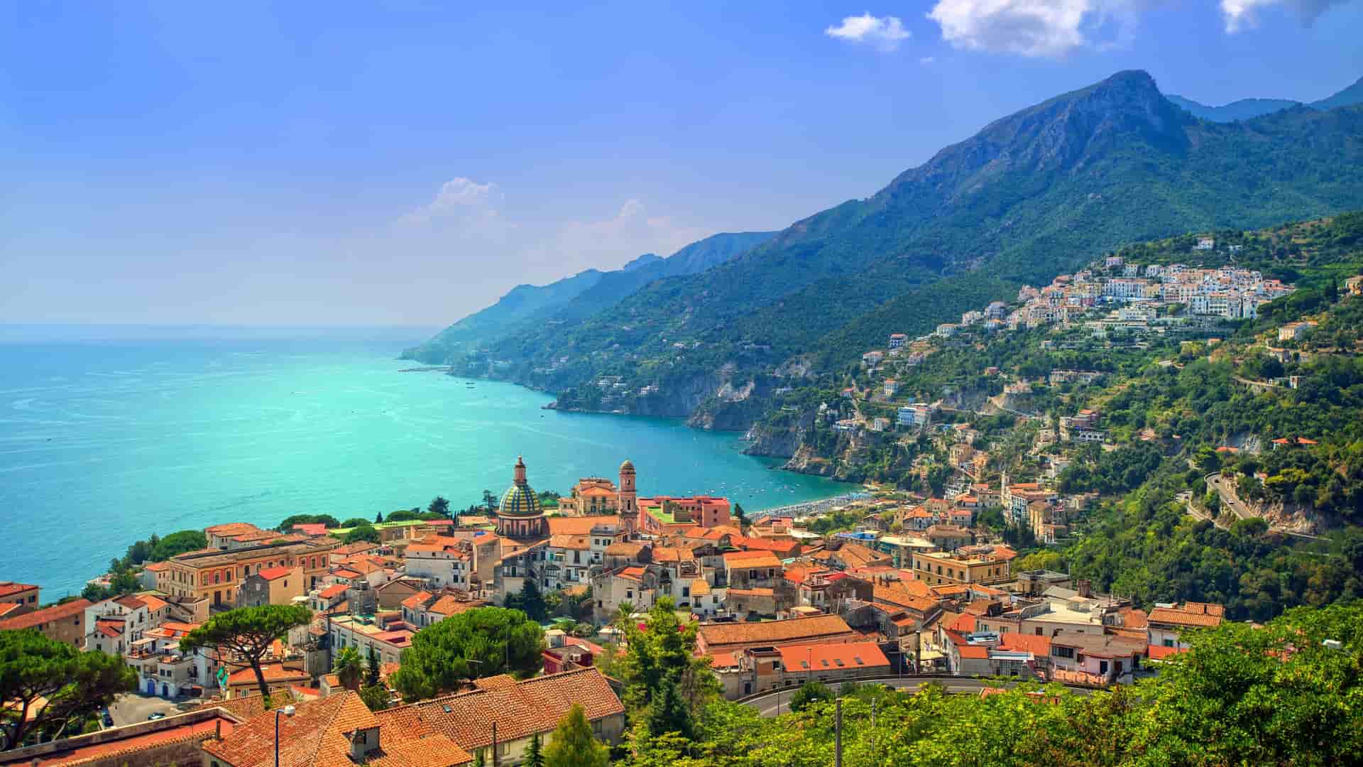 A breathtaking, elevated view of the stunning Amalfi Coast near Salerno, Italy, with colorful houses clinging to the steep hillsides that plunge into the turquoise Tyrrhenian Sea.
