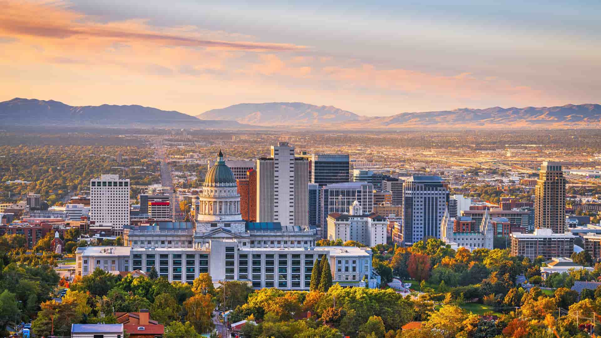 "A stunning sunset panoramic view of downtown Salt Lake City, Utah, with the historic State Capitol building in the foreground, and the dramatic Wasatch Mountains in the distance. "