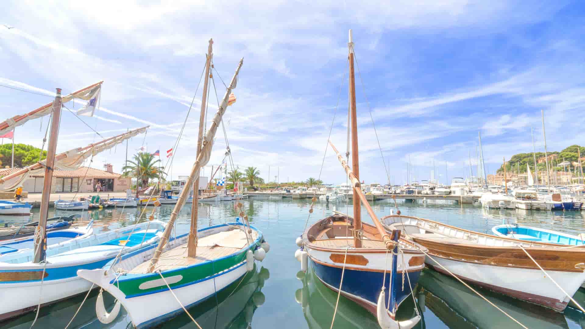 A close-up view of traditional, colorful wooden fishing boats called 'pointus' docked in the picturesque harbor of Sanary-sur-Mer, France, under a bright, sunny sky.