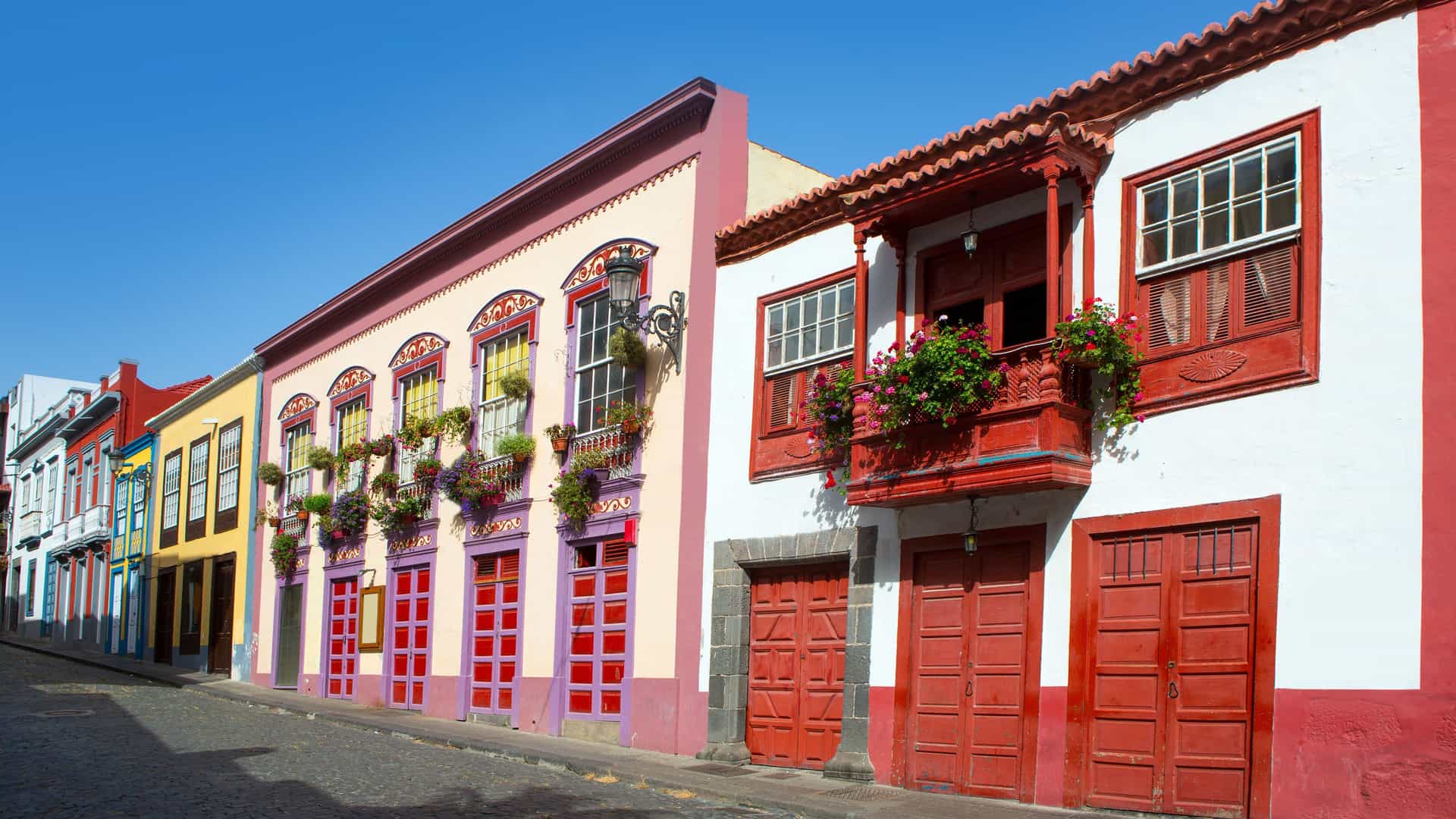 A street view of traditional colonial buildings with bright, colorful facades and wooden balconies, in the historic town of Santa Ana Island, Colombia.