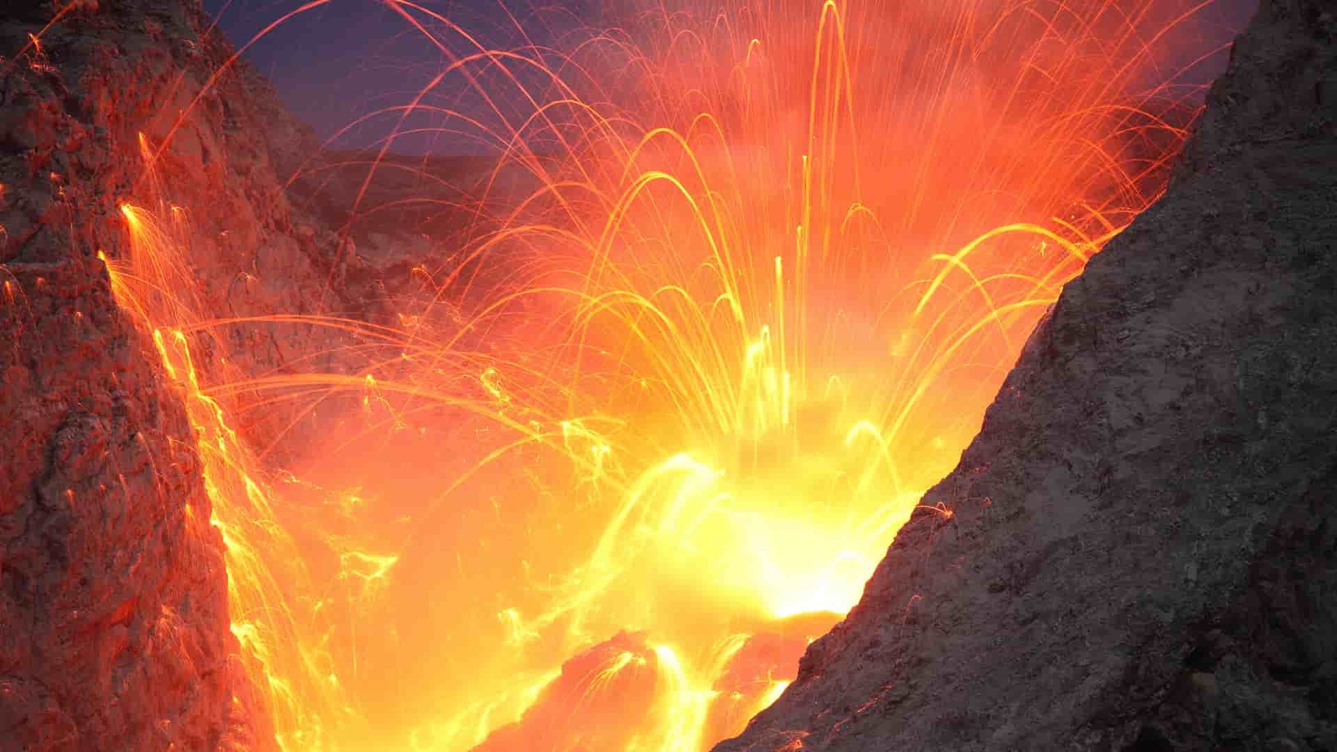 A breathtaking close-up of the active Batu Tara volcano, with incandescent lava explosions and fiery arcs of molten rock erupting into the night sky.