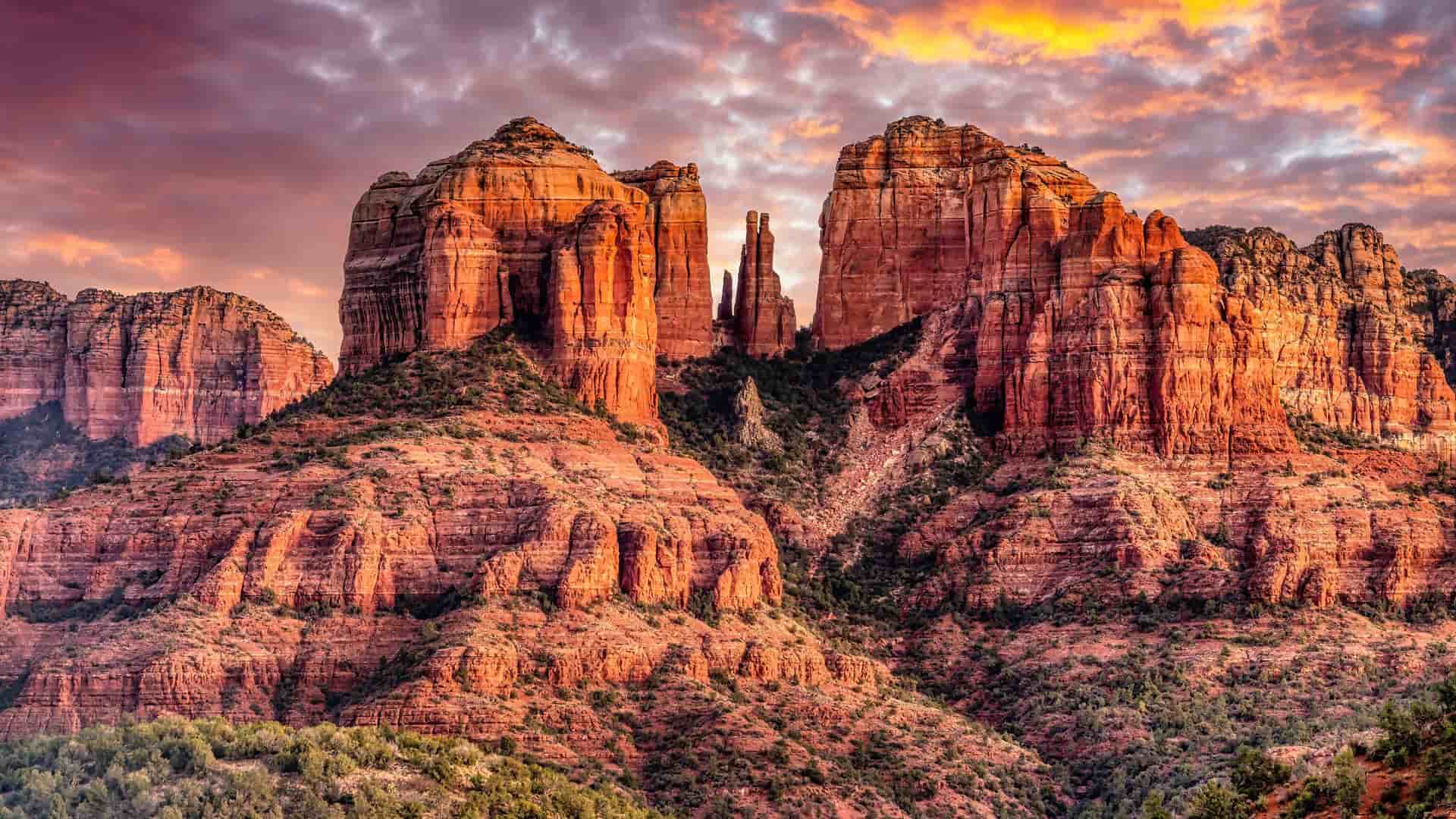 "A beautiful sunset over the dramatic red rock formations and iconic spires of the Sedona, Arizona desert landscape, with a colorful sky. "