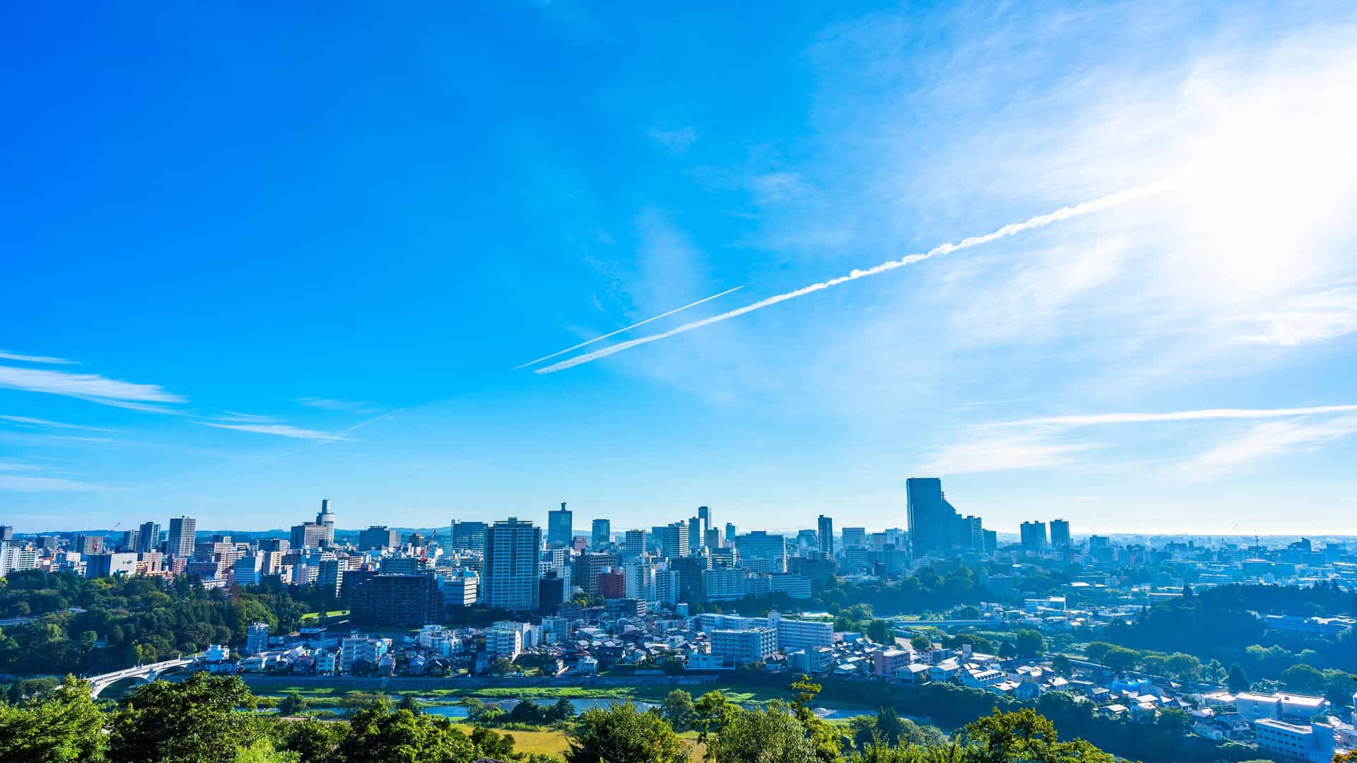 A scenic wide-angle view of the Sendai skyline in Tohoku, Japan, with its modern buildings and cityscape under a clear blue sky.