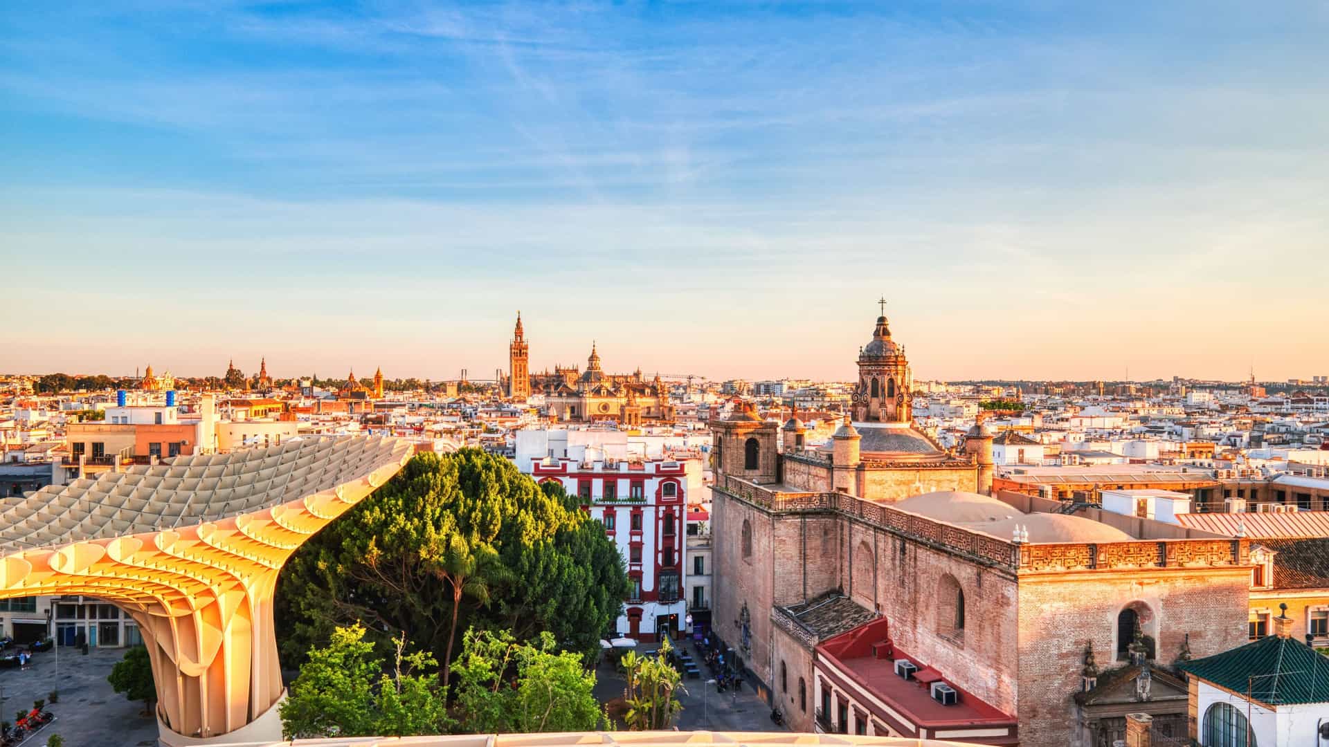 "A stunning sunset view of the Seville, Spain skyline, showcasing the iconic Metropol Parasol, historic cathedrals, and charming architecture under a beautiful sky. "