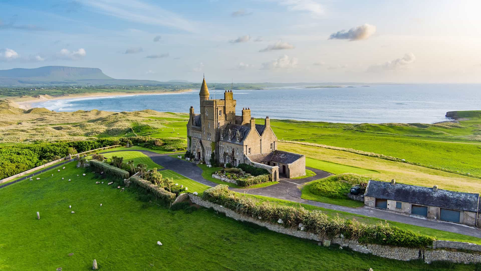 "An aerial view of the iconic Mullaghmore Castle in Sligo, Ireland, a historic castle on a lush green hilltop overlooking the Atlantic Ocean. "