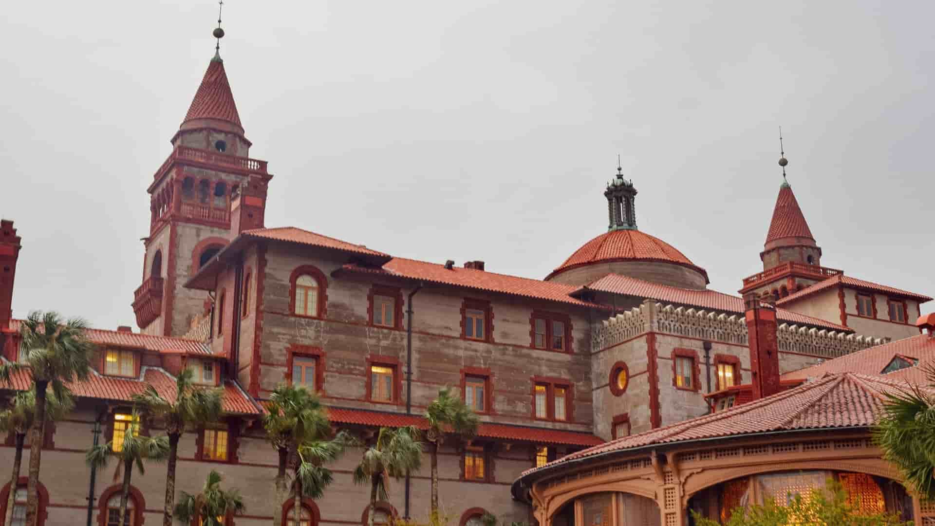 The former Ponce de León Hotel is a Spanish Renaissance Revival structure with red tile roofs and towers, surrounded by palm trees.