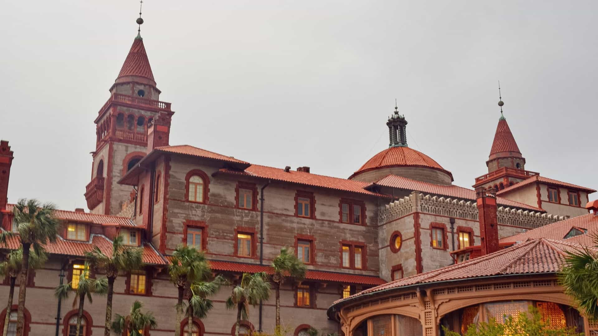 The former Ponce de León Hotel is a Spanish Renaissance Revival structure with red tile roofs and towers, surrounded by palm trees.