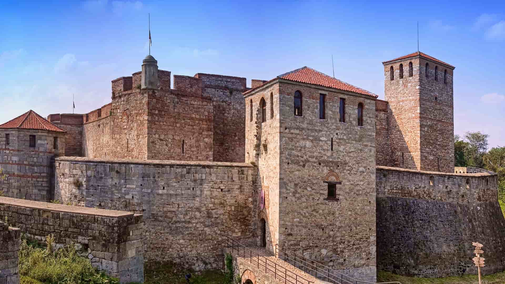 A historic view of the Baba Vida Fortress, a medieval castle with thick stone walls and towers, a major landmark in Vidin, Bulgaria, under a blue sky.