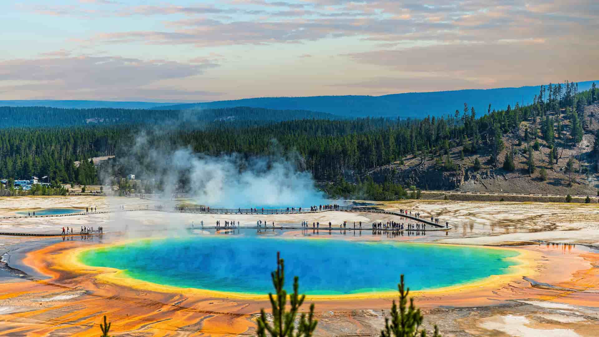 "A vibrant aerial shot of the Grand Prismatic Spring in Yellowstone National Park, Wyoming, with its stunning, multi-colored bacterial mats and steam rising from the hot spring."