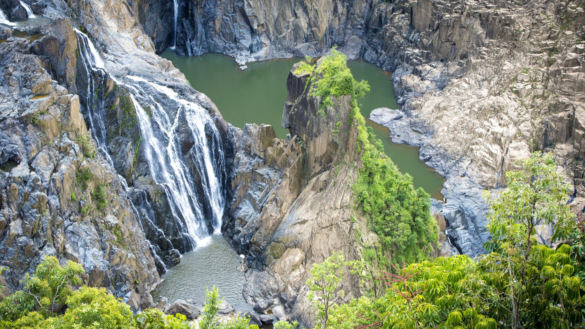 A dramatic view of Barron Falls, a powerful waterfall flowing into a rocky gorge in the Barron Gorge National Park in Queensland, Australia.