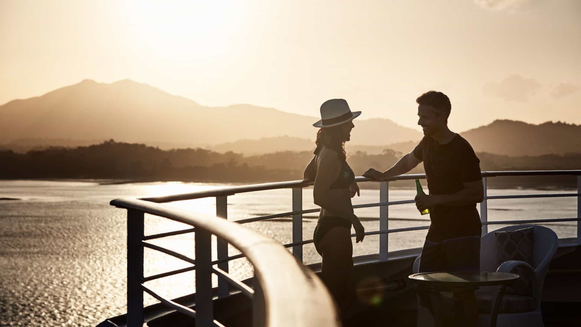 A couple enjoys a golden sunset from the deck of a Princess Cruises ship, cruising through the scenic waters of the Panama Canal.