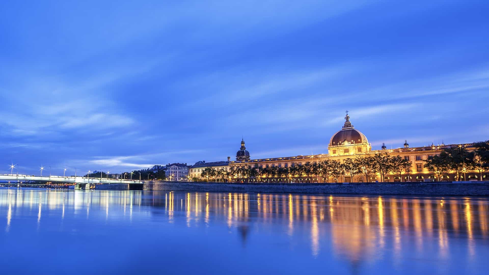 the Hotel-Dieu de Lyon at night on the banks of the Rhone River in Lyon, France