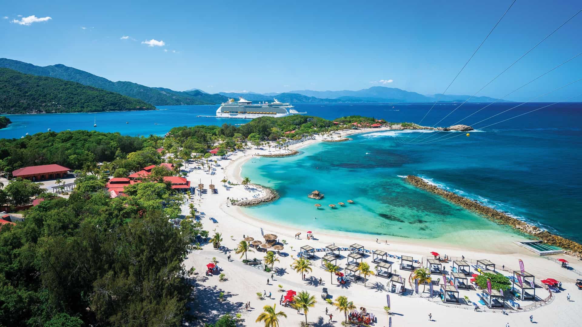 An aerial view of Royal Caribbean's private destination, Labadee, Haiti, showcasing pristine beaches, a cruise ship docked in the bay, and lush green hills, a perfect day for relaxation and adventure.