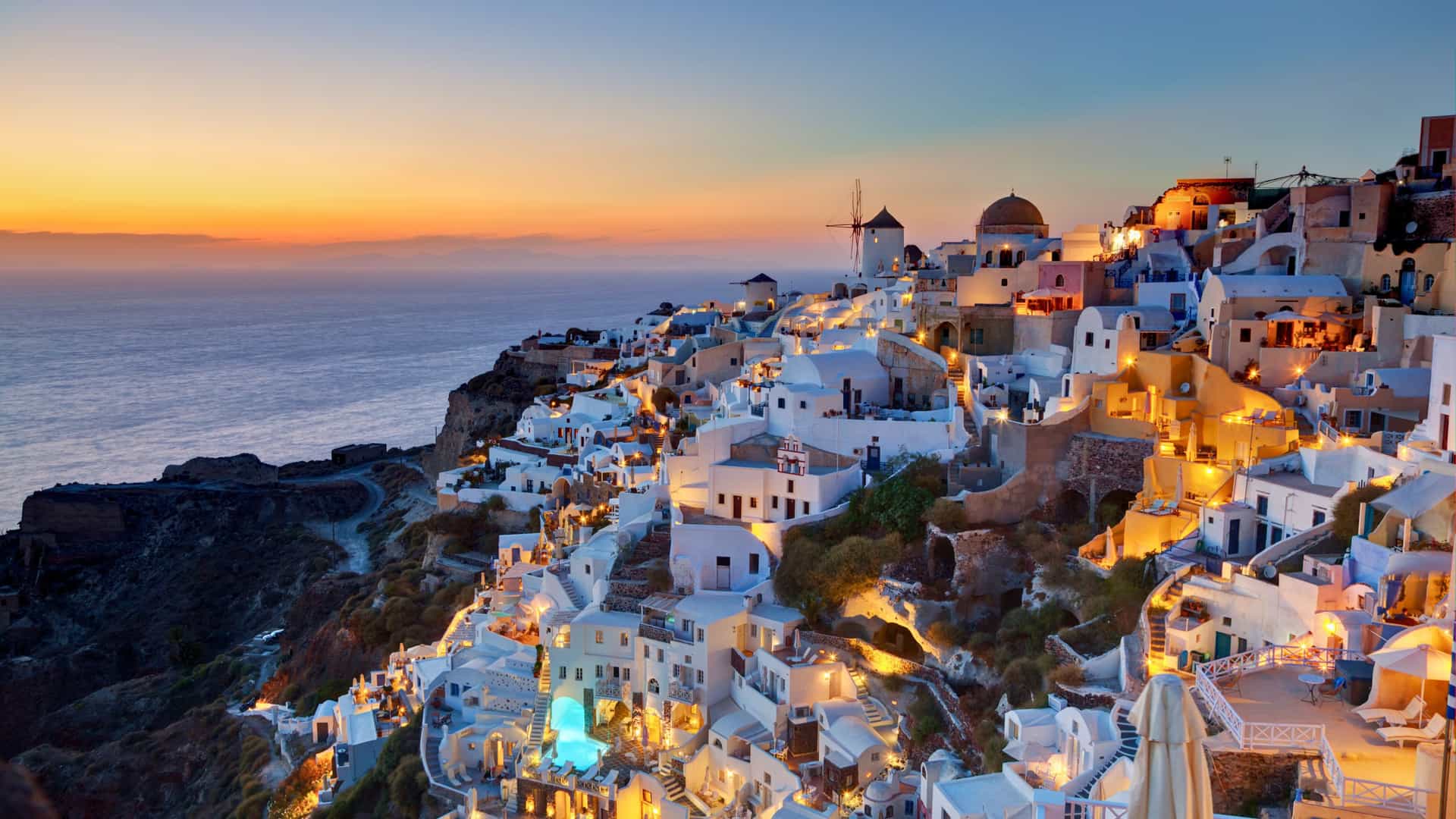 A Royal Caribbean cruise ship visits Santorini, Greece, a Mediterranean destination known for its white hillside villages illuminated by the setting sun.