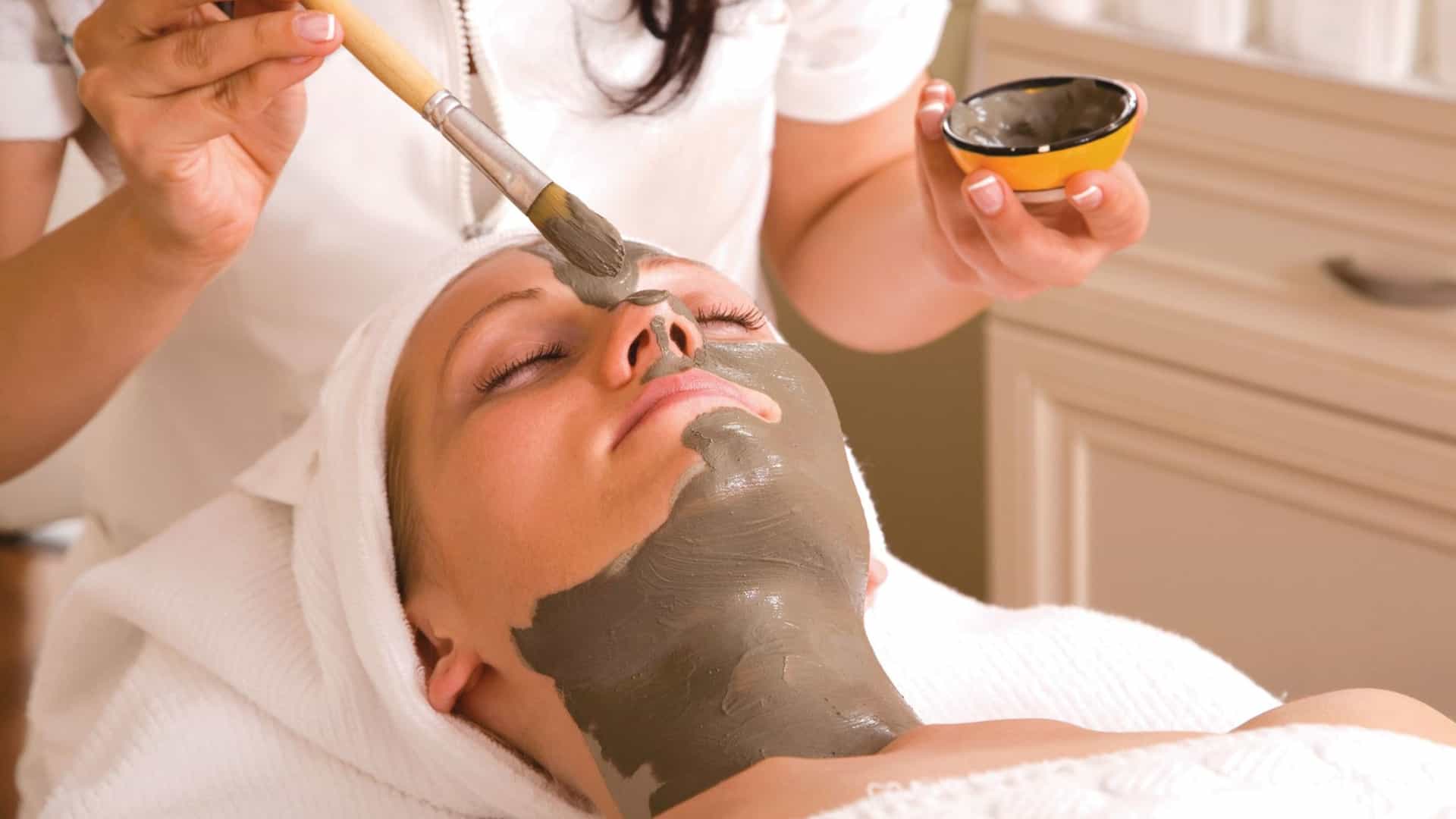 A close up of women at Seabourn's spa relaxing and getting a mud facial painted on by brush.