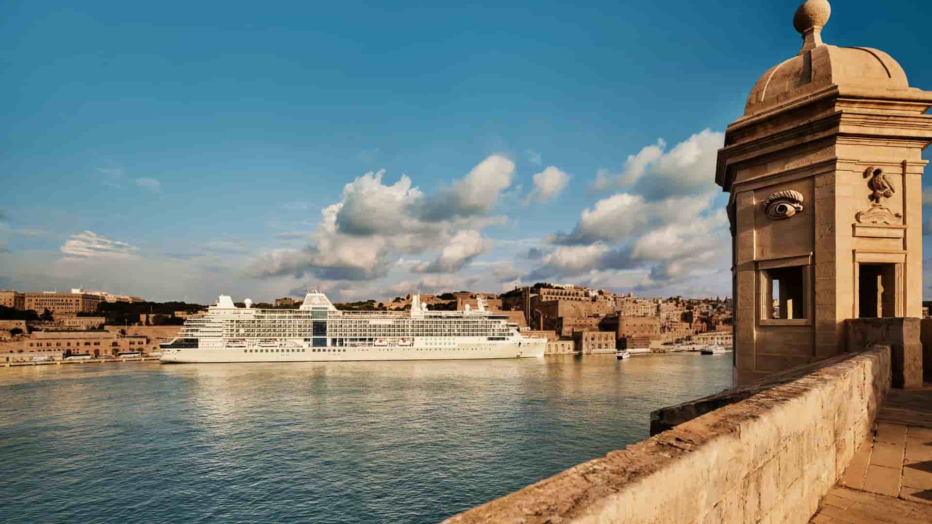 Silversea luxury cruise ship docked in the historic harbor of Valletta, Malta, with ancient fortifications visible in the foreground.