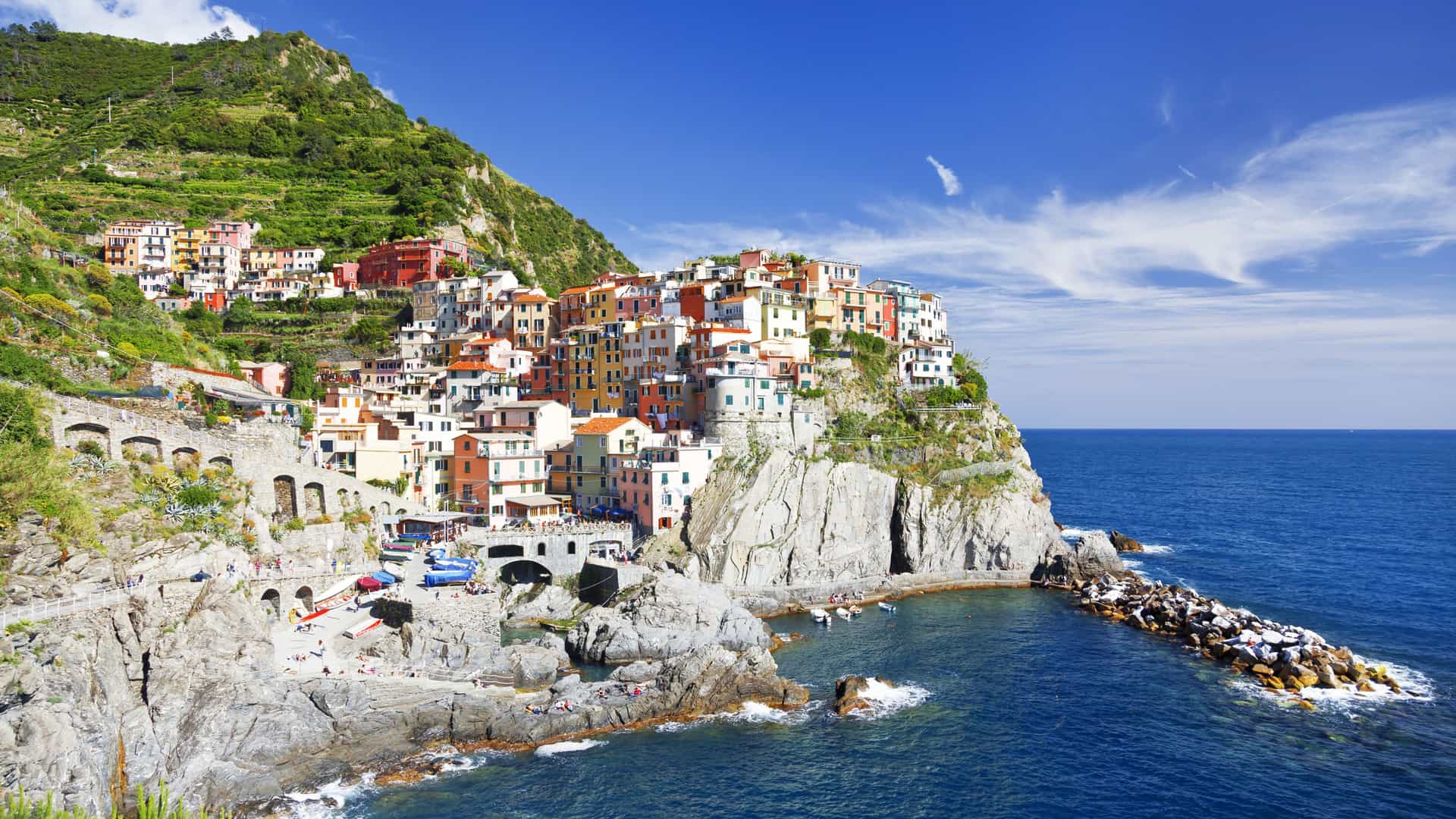 Colorful cliffside village perched above a rocky Mediterranean coastline and blue sea on a Tauck small ship cruise.