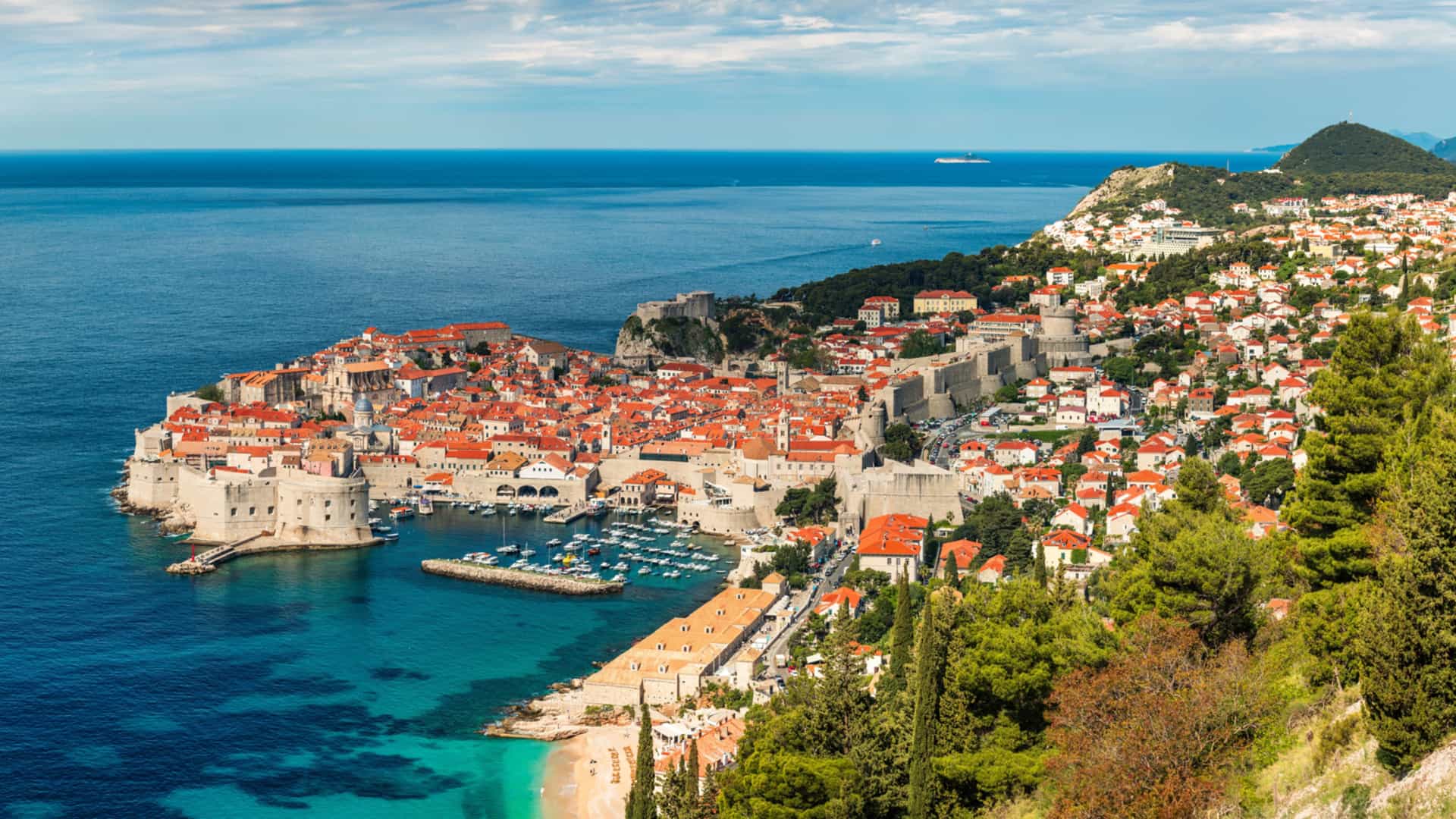 A stunning aerial view of Dubrovnik on the Dalmatian Coast, showcasing its medieval stone walls, orange‑tiled rooftops, and turquoise Adriatic waters surrounding the historic old town.