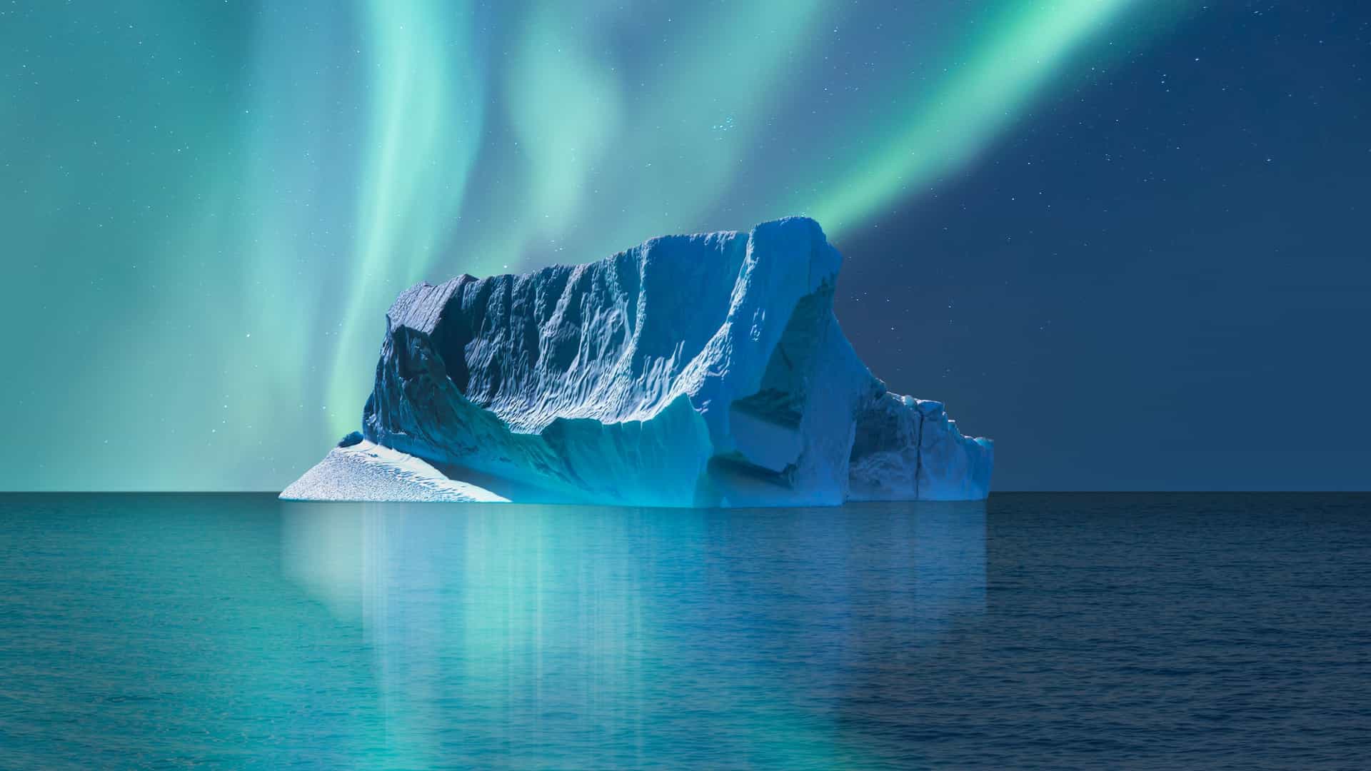 A towering blue‑white iceberg floating in the Greenland Sea beneath vibrant green aurora borealis, reflecting in calm Arctic water and showcasing the dramatic polar scenery of this remote North Atlantic region.