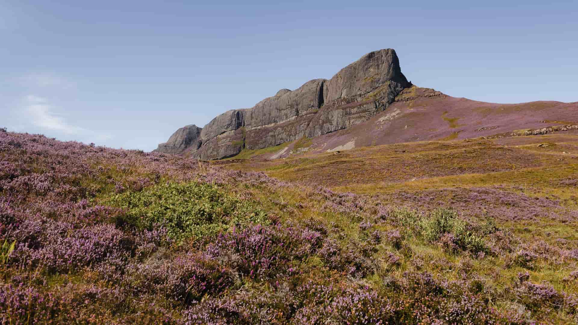 A magnificent wide landscape view of An Sgùrr, the dramatic pitchstone ridge that dominates the Isle of Eigg in the Inner Hebrides, Scotland—a legendary destination for coastal island excursions.