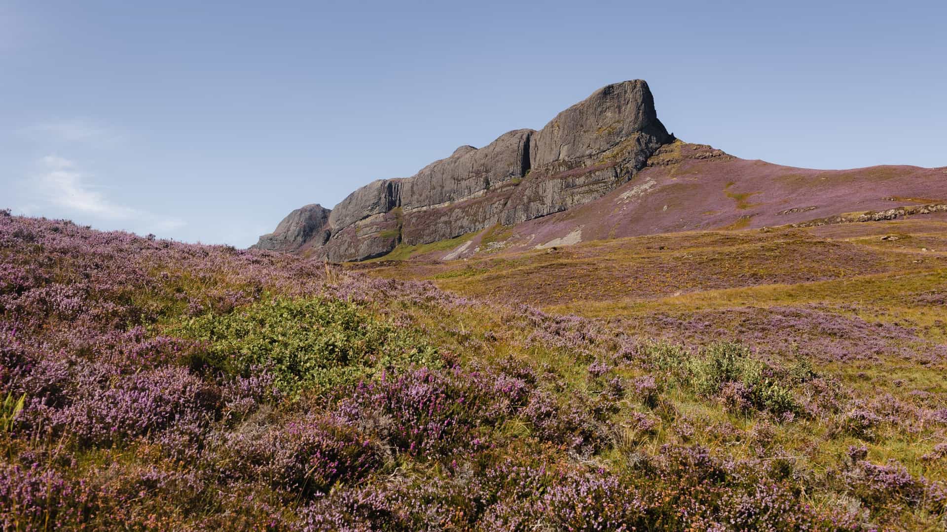 A magnificent wide landscape view of An Sgùrr, the dramatic pitchstone ridge that dominates the Isle of Eigg in the Inner Hebrides, Scotland—a legendary destination for coastal island excursions.
