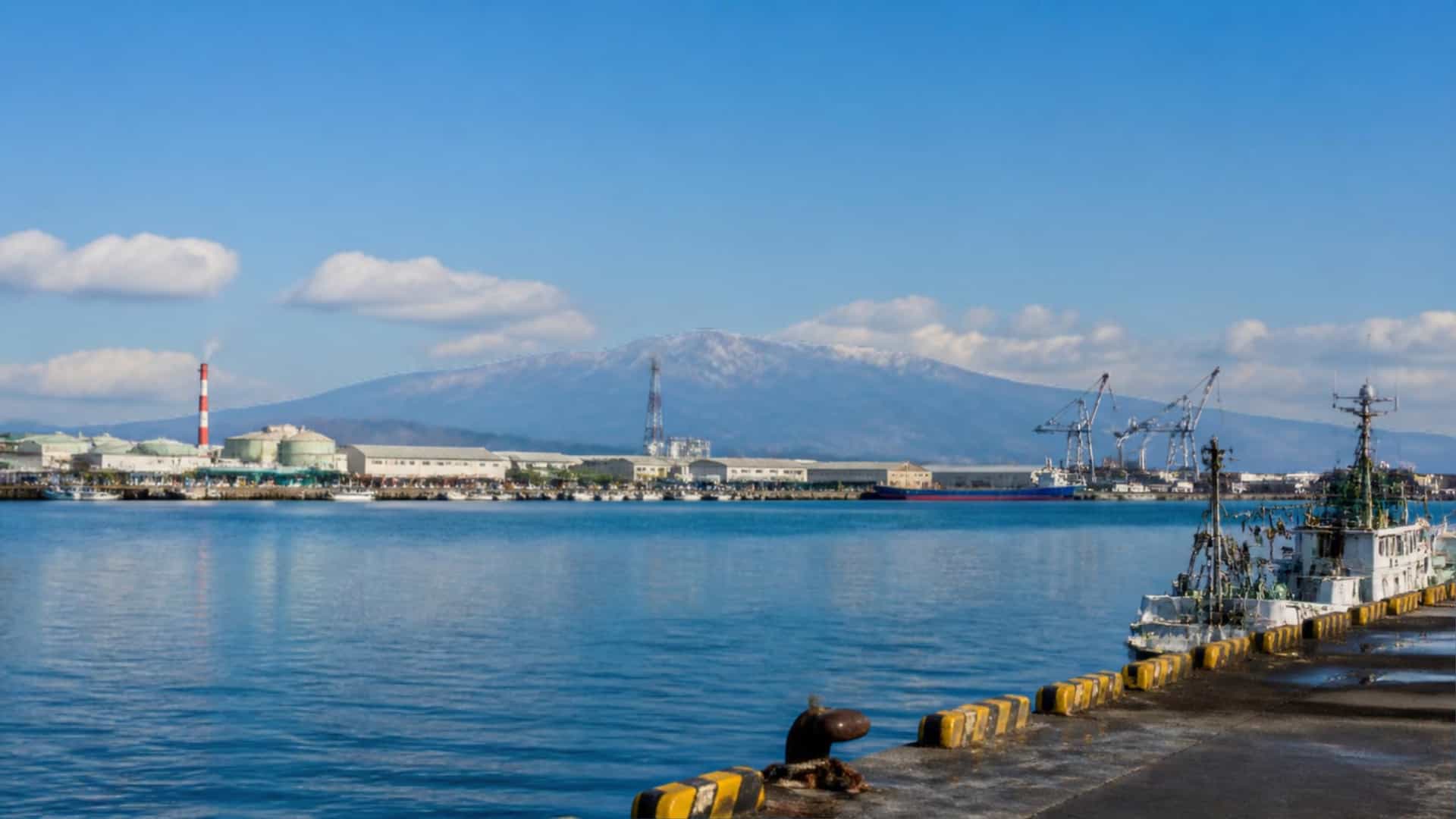 The port city of Tomakomai, Hokkaido, Japan, with its harbor and distant mountains under a wide northern sky.