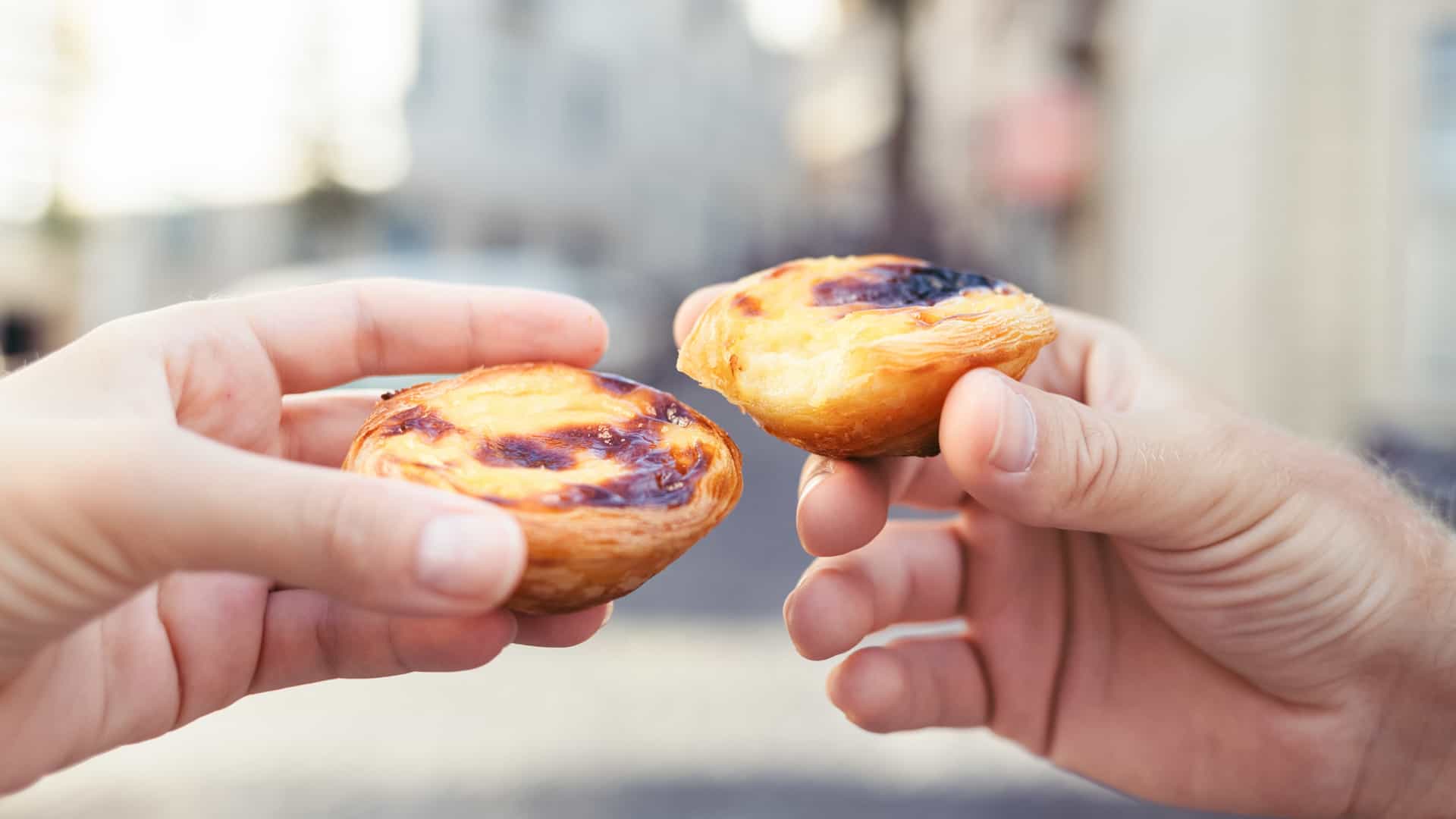 Traditional portuguese desserts in woman's and man's hands. Pastel de Nata.
