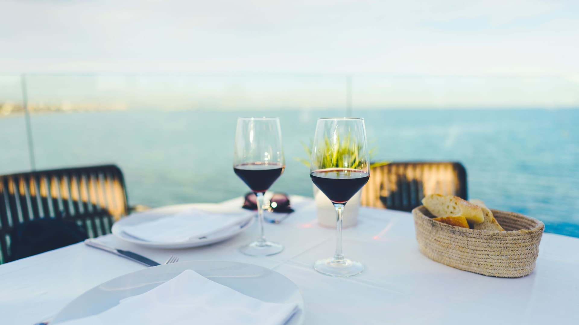 Two glasses of wine on a table with the ocean in the background.