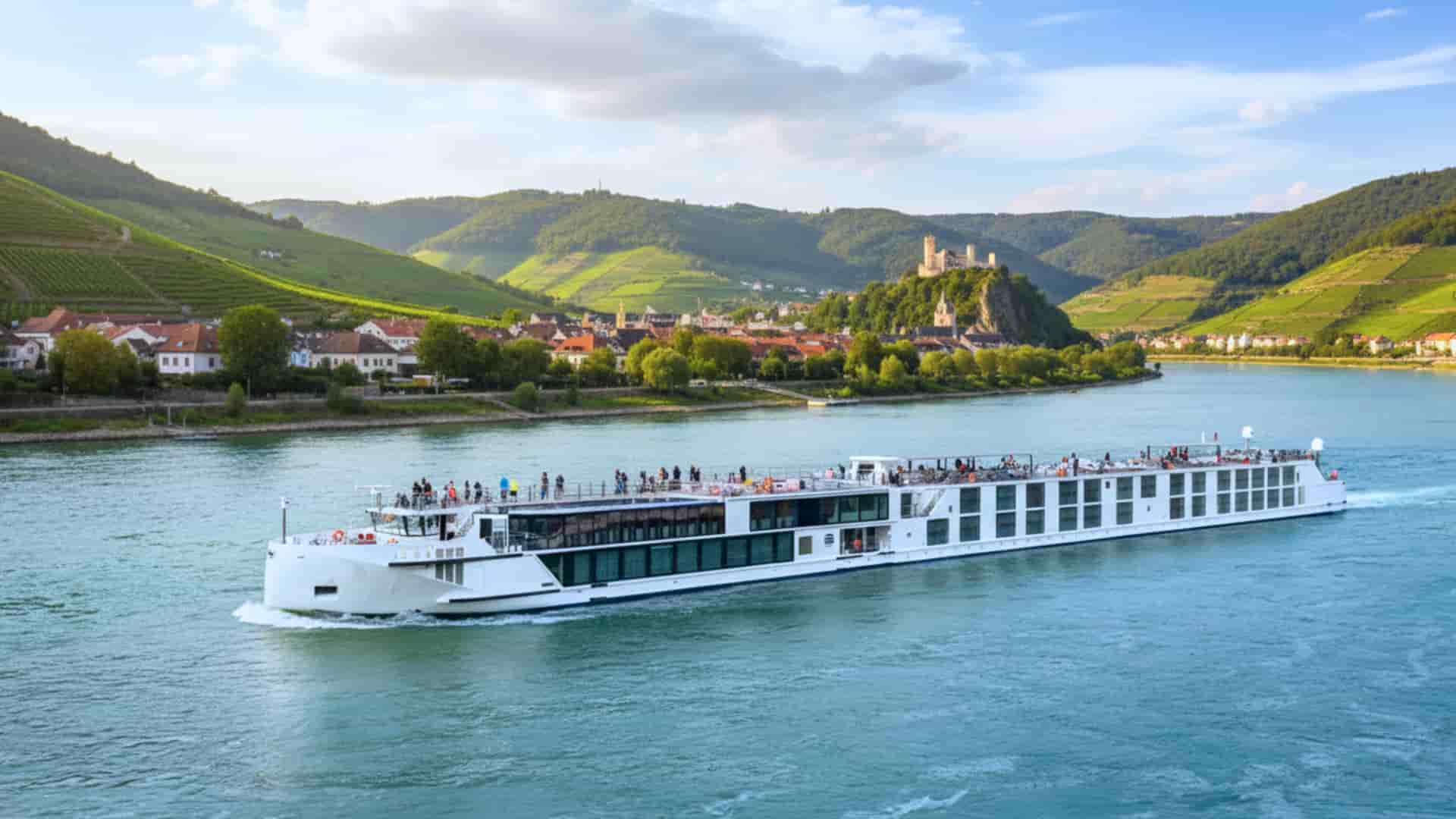 Uniworld S.S. Emilie river cruise ship exterior with a lucious green mountain range in the background.