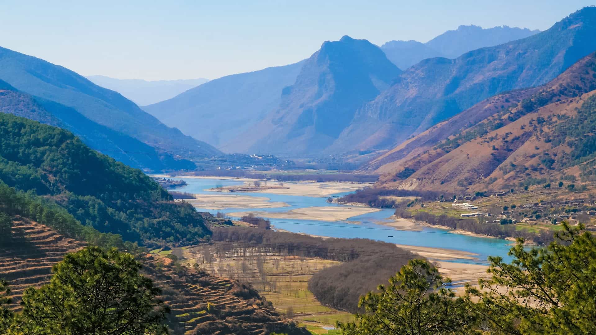 A wide view of the Yangtze River winding through a mountainous landscape in Asia, highlighting the scenic beauty of a Uniworld river cruise destination.