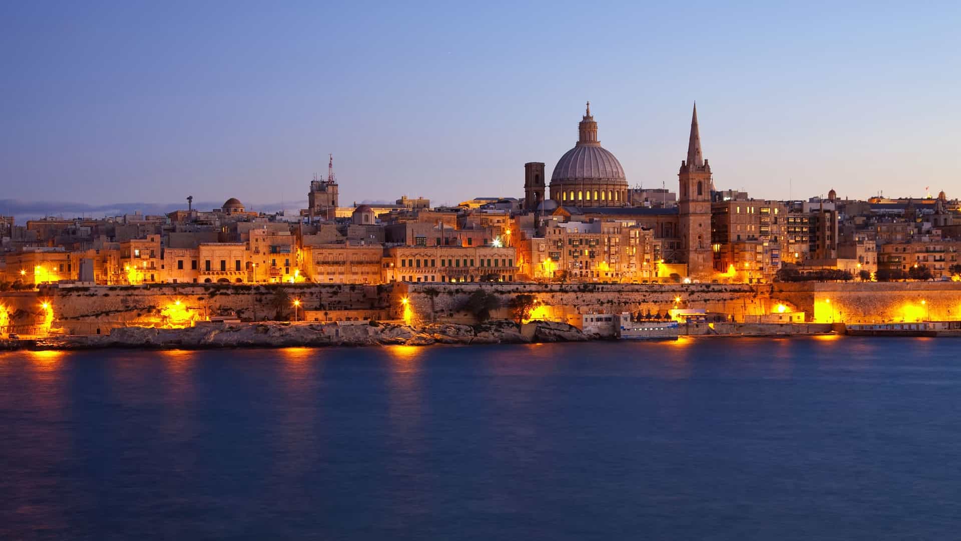 Valletta, Malta skyline with illuminated buildings at dusk.