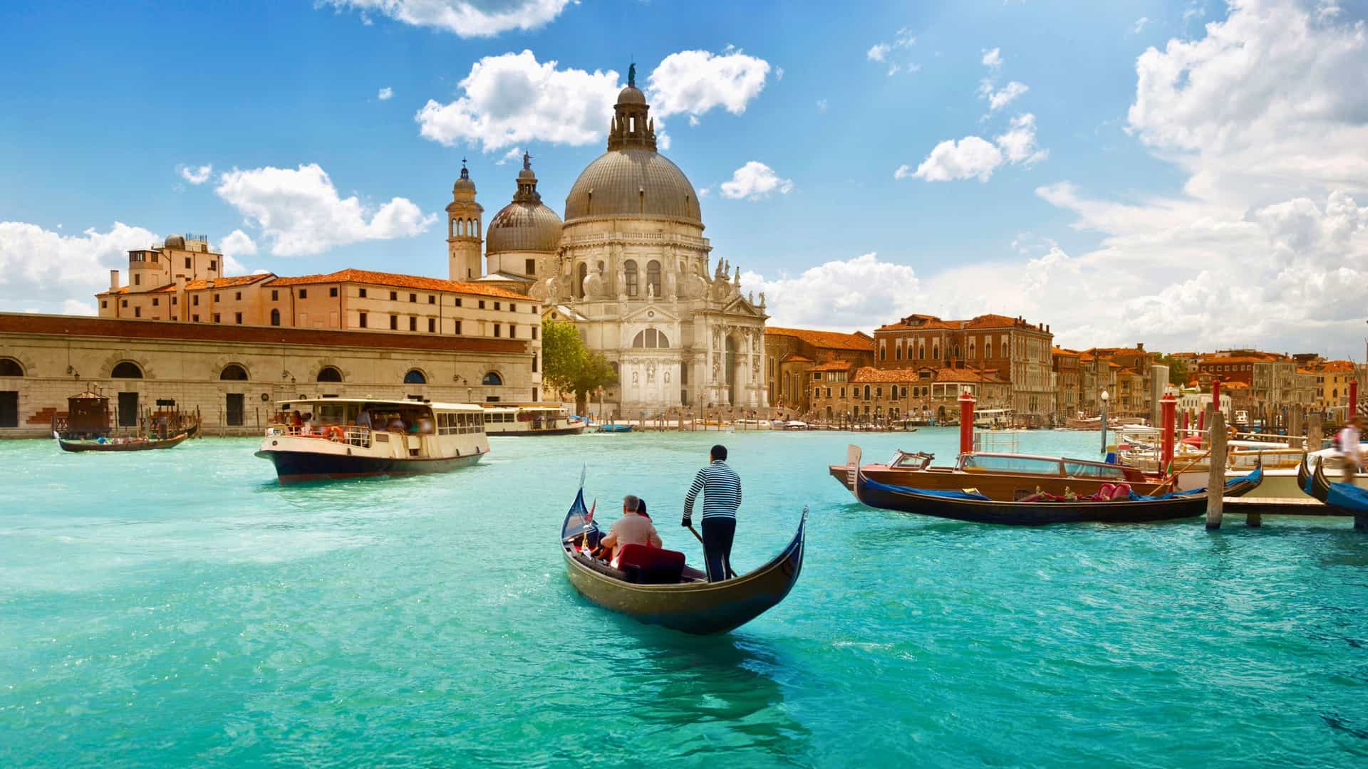 Venice Grand Canal in Europe with a gondola, the Basilica di Santa Maria della Salute, and a Holland America Line cruise ship in the background.
