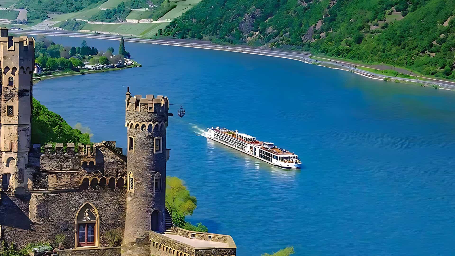Aerial of Viking Hervor sailing a European river with a castle in the foreground.