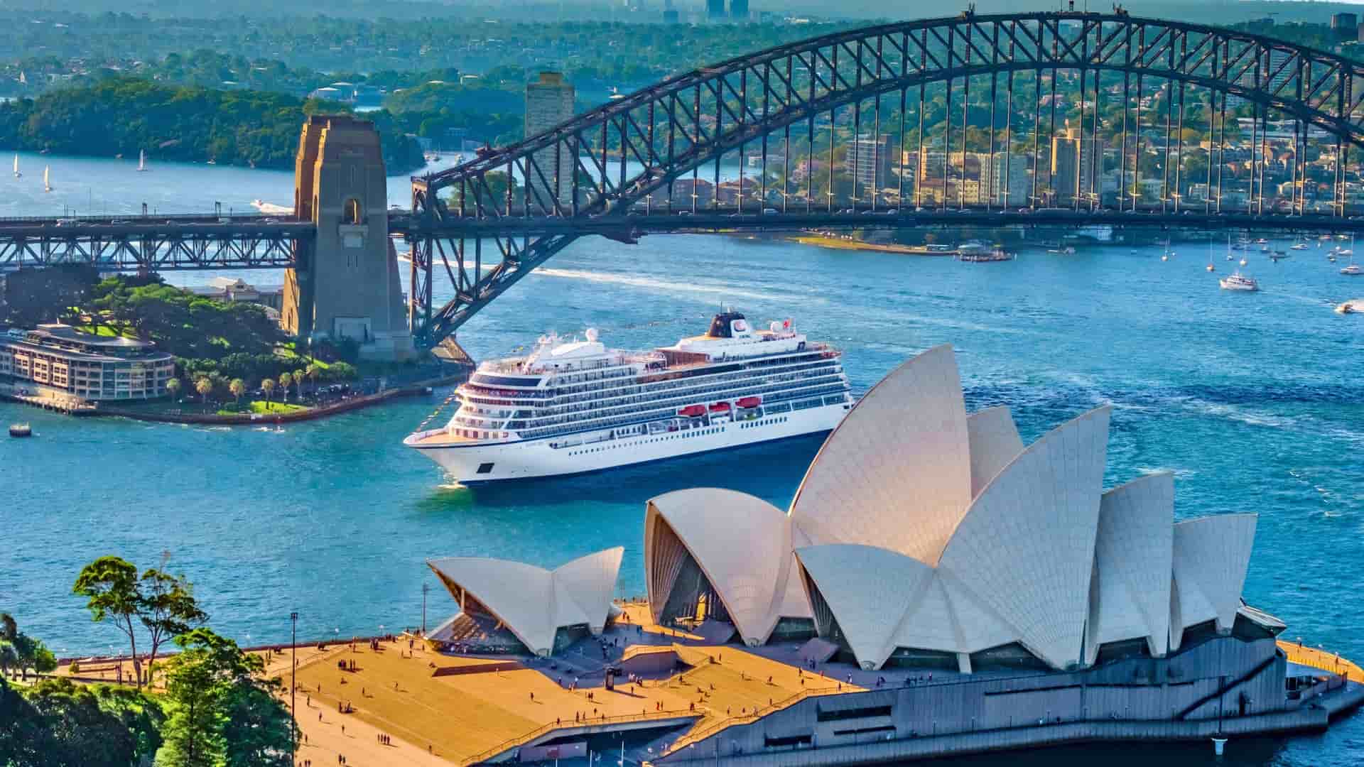 A Viking Ocean cruise ship sailing past the iconic Sydney Opera House and Sydney Harbour Bridge in Australia, a featured destination on a Viking World Cruise.