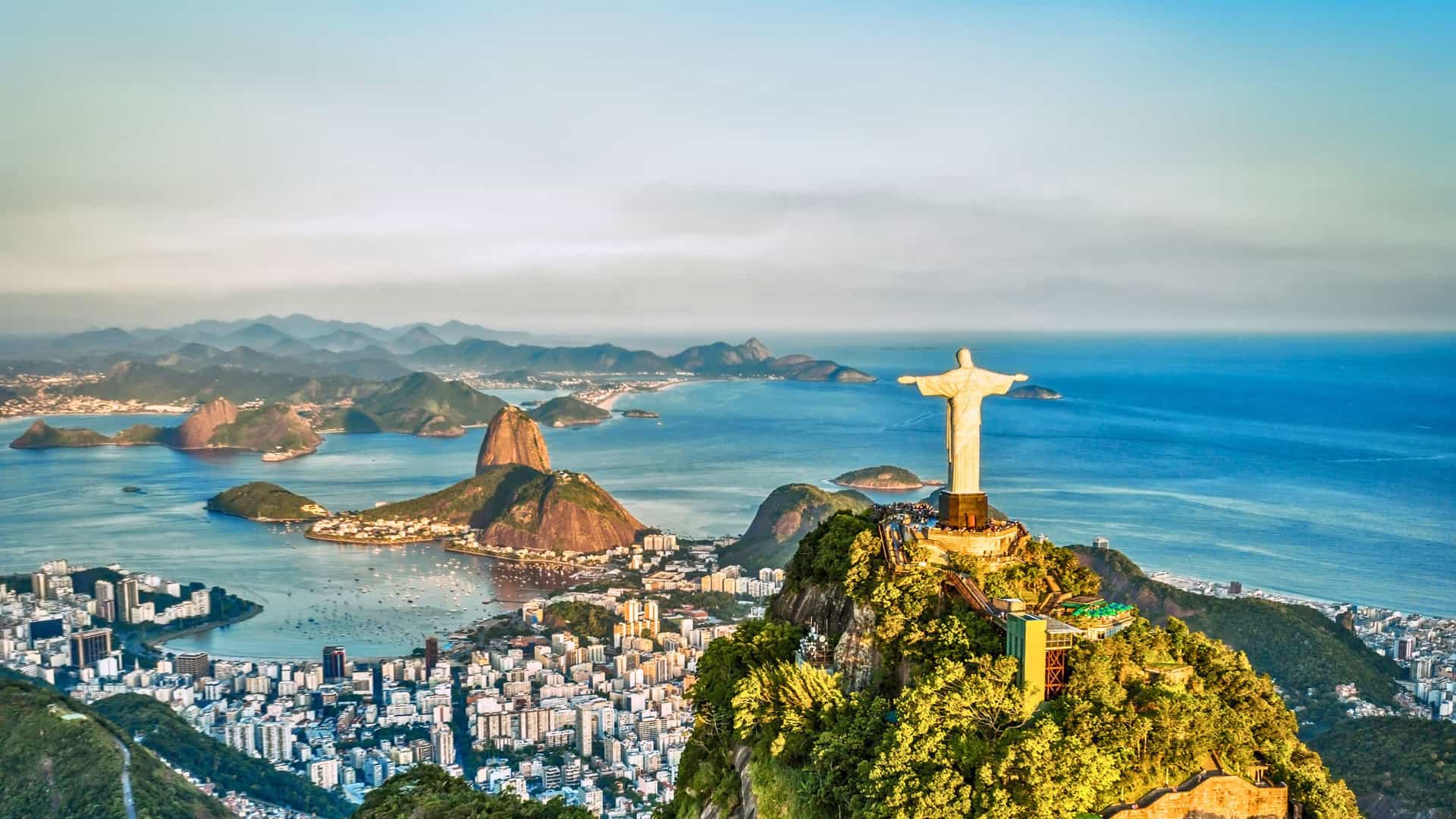 An iconic view of the Christ the Redeemer statue overlooking the city of Rio de Janeiro, Brazil, and Sugarloaf Mountain, a breathtaking port of call on a Viking Ocean cruise to South America.