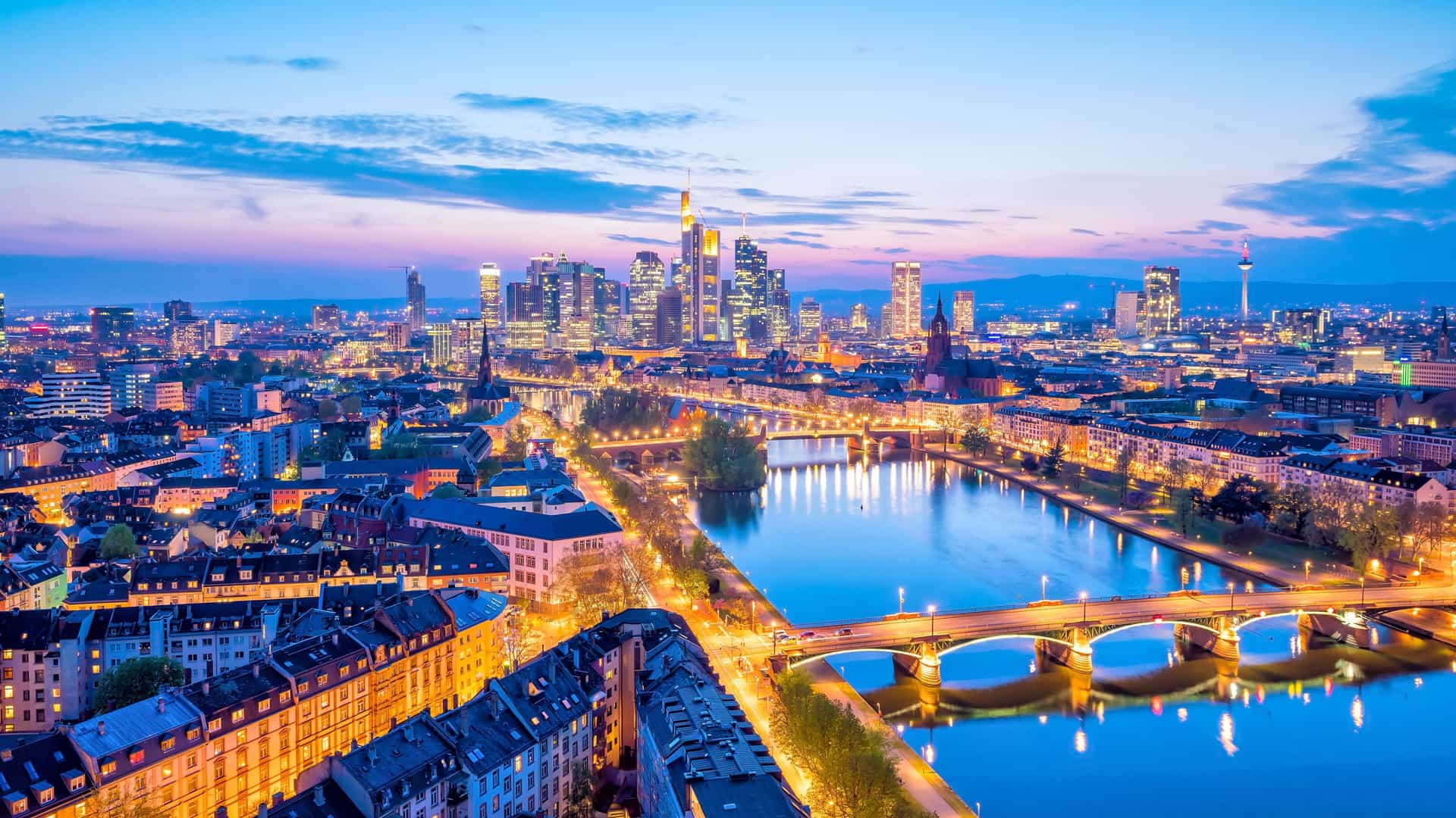 Evening view of a European city along the Main River with illuminated bridges and skyline, featured on Viking Ocean Cruises' river excursions.