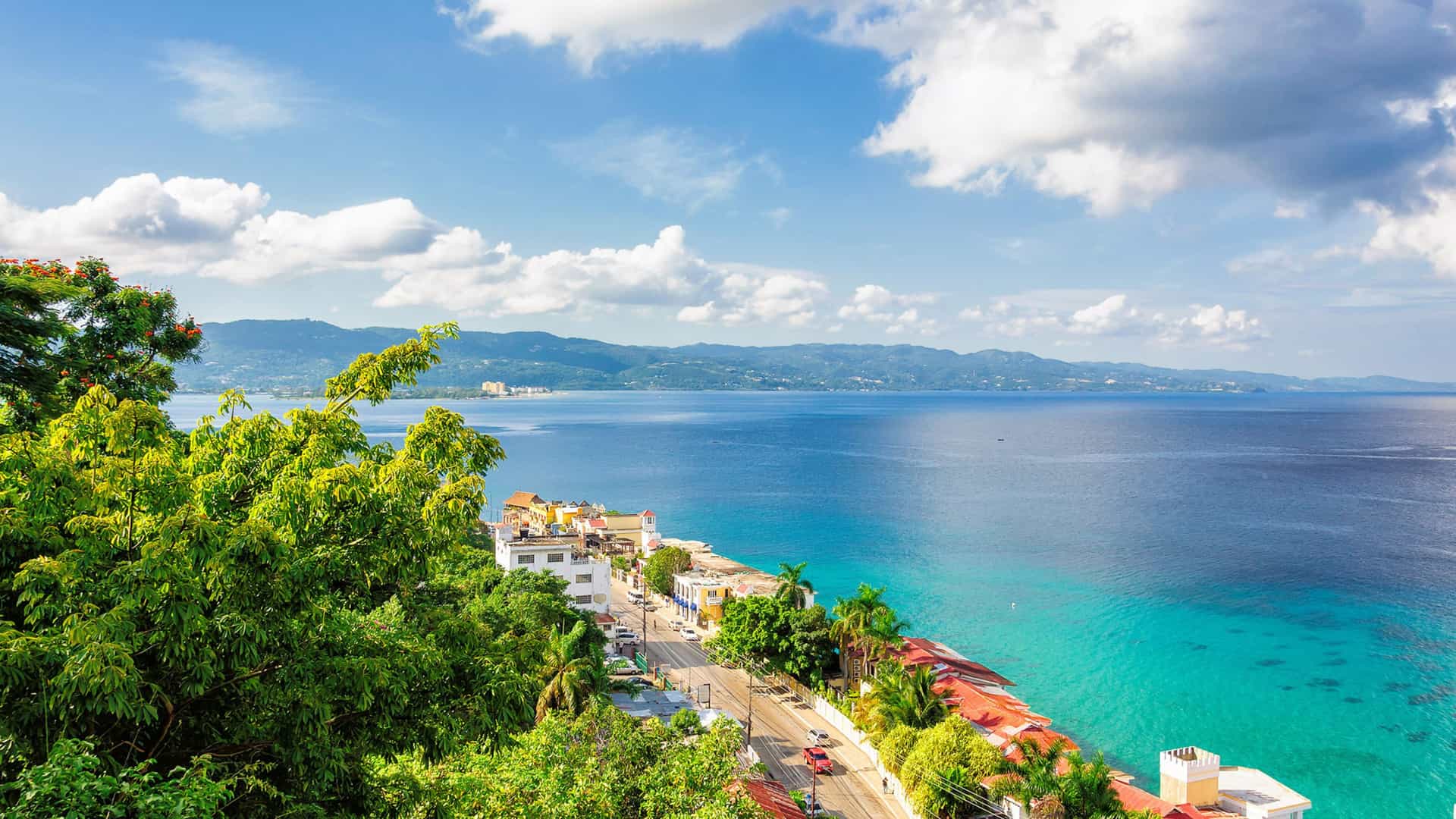An aerial view of the vibrant coastal town of Montego Bay, Jamaica, with its turquoise waters and lush green hills, a beautiful port of call on a Viking Ocean cruise to the Western Caribbean.