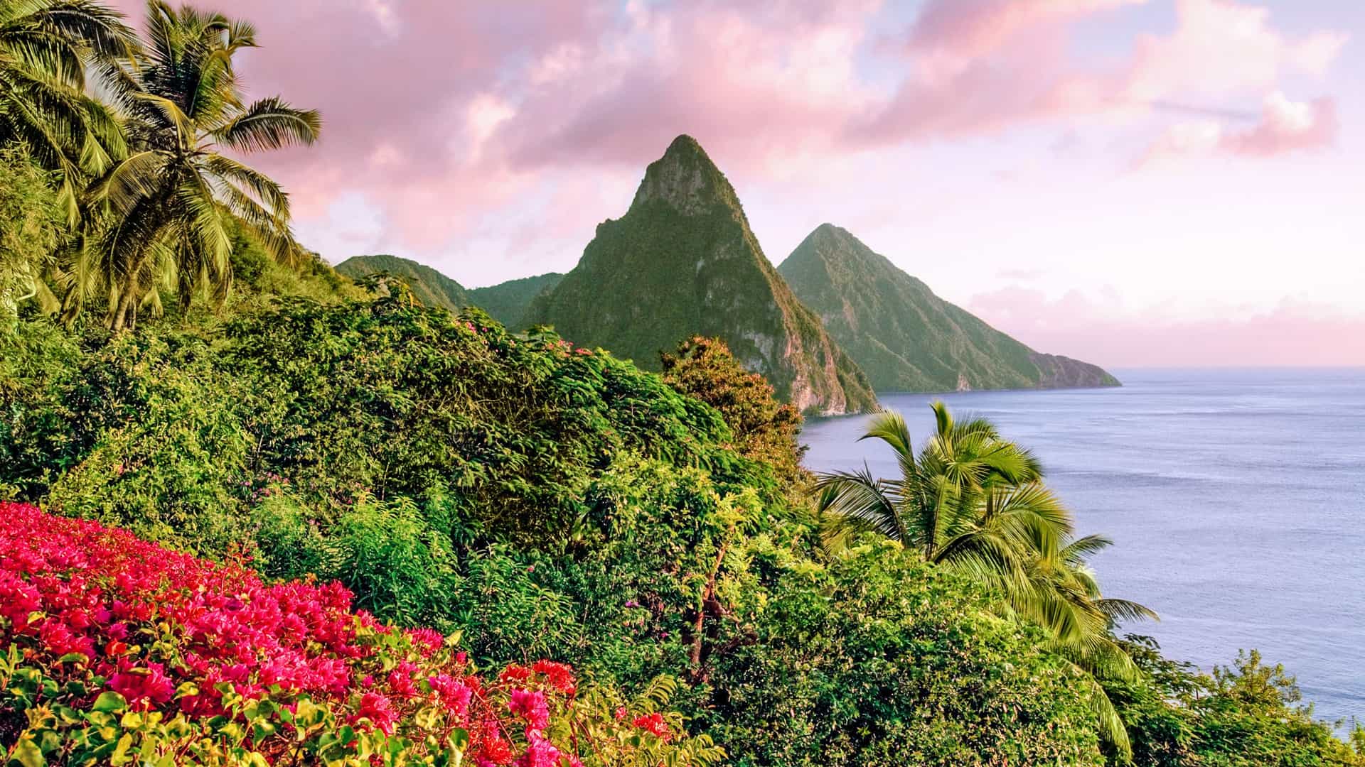 The iconic Pitons mountains towering over the lush, tropical landscape and calm waters of St. Lucia, a breathtaking port of call on a Viking Ocean cruise to the Southern Caribbean.